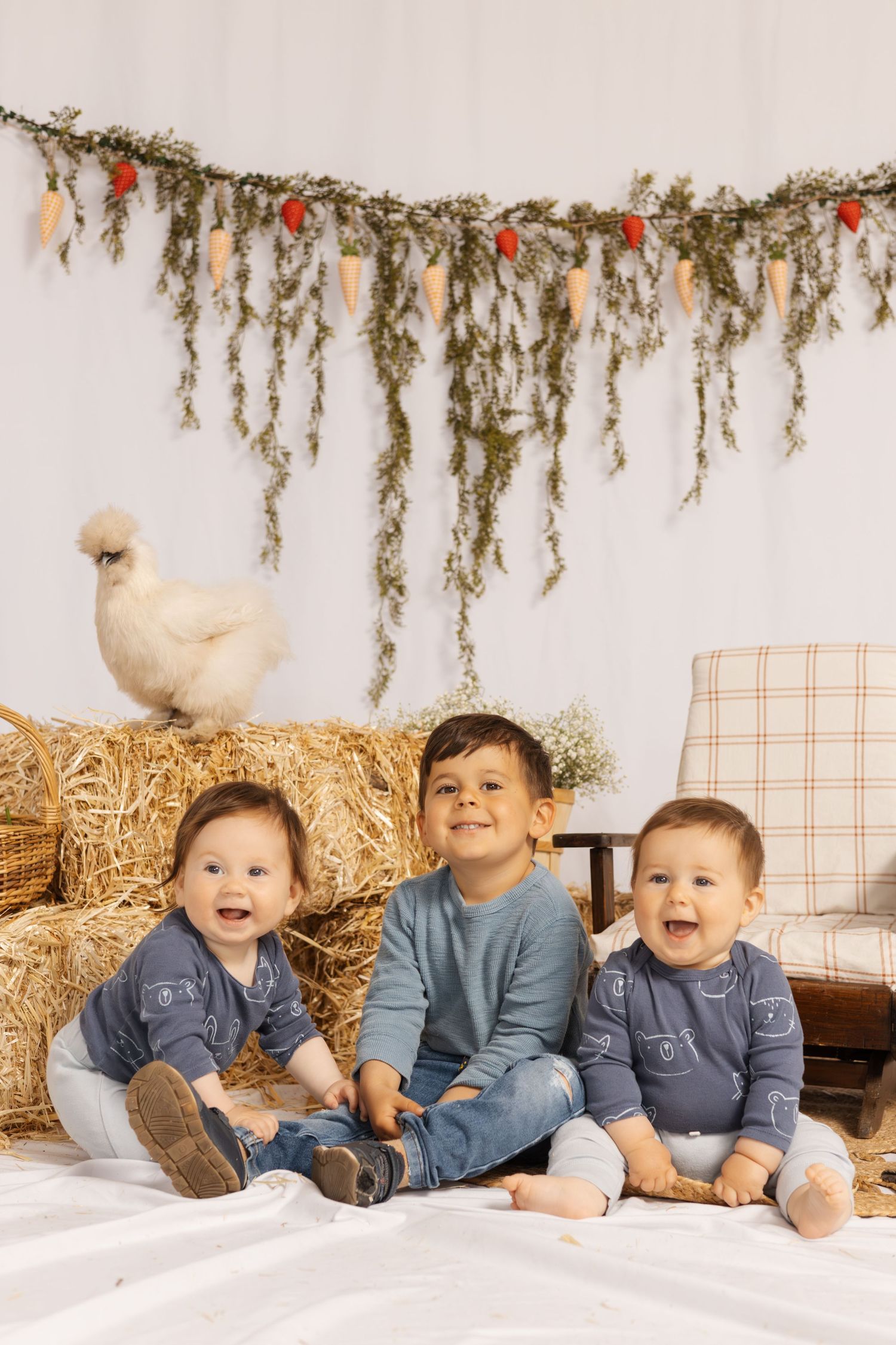 Children in coordinating outfits pose on hay bales with festive garland and decorations.