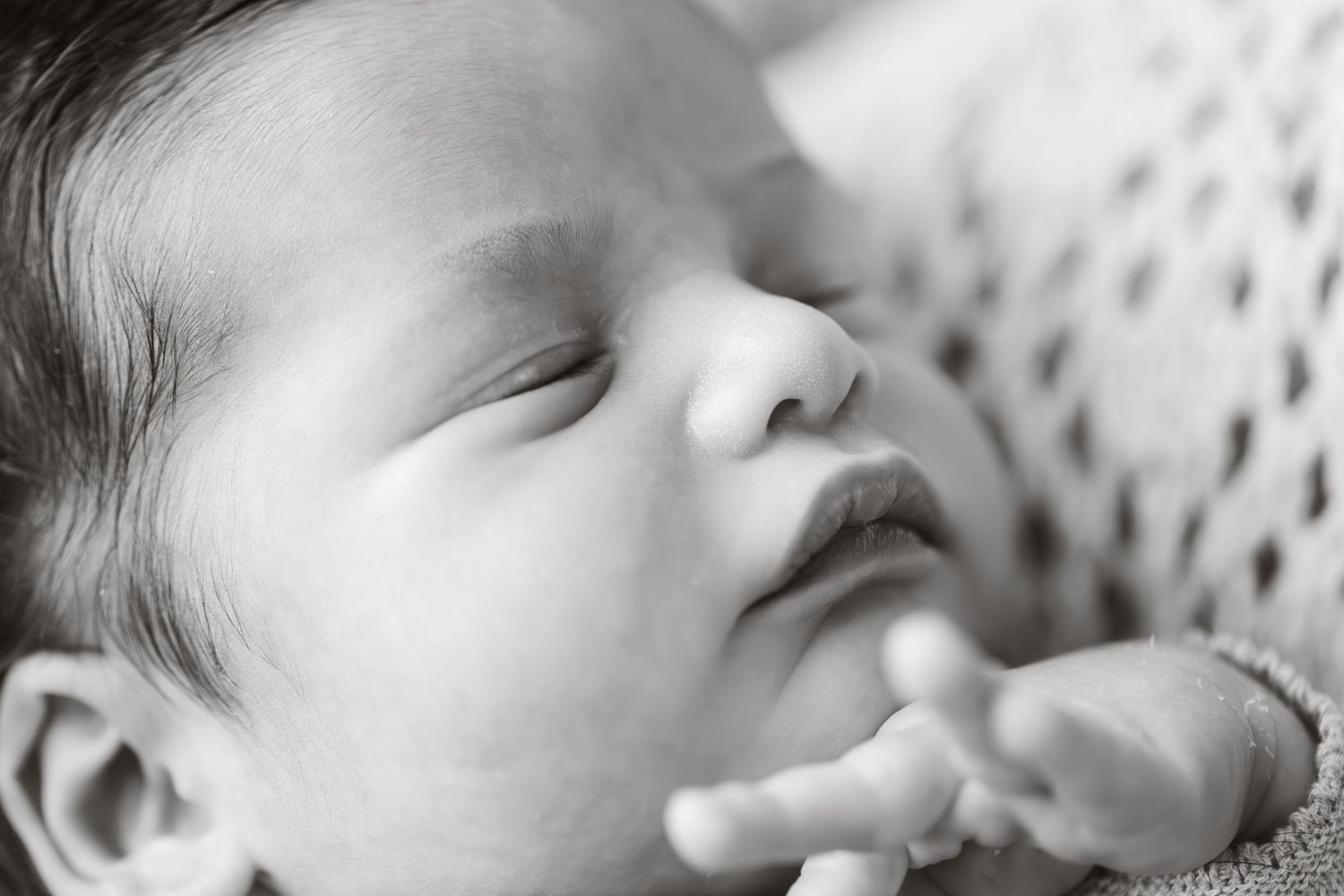 Close-up black and white portraits of a sleeping newborn baby with peaceful expression.