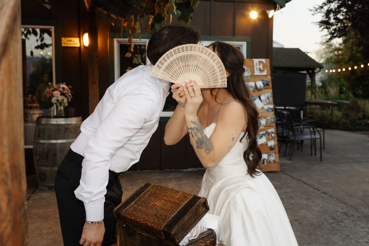 Evening outdoor wedding reception scene with warm lighting and wooden beams.