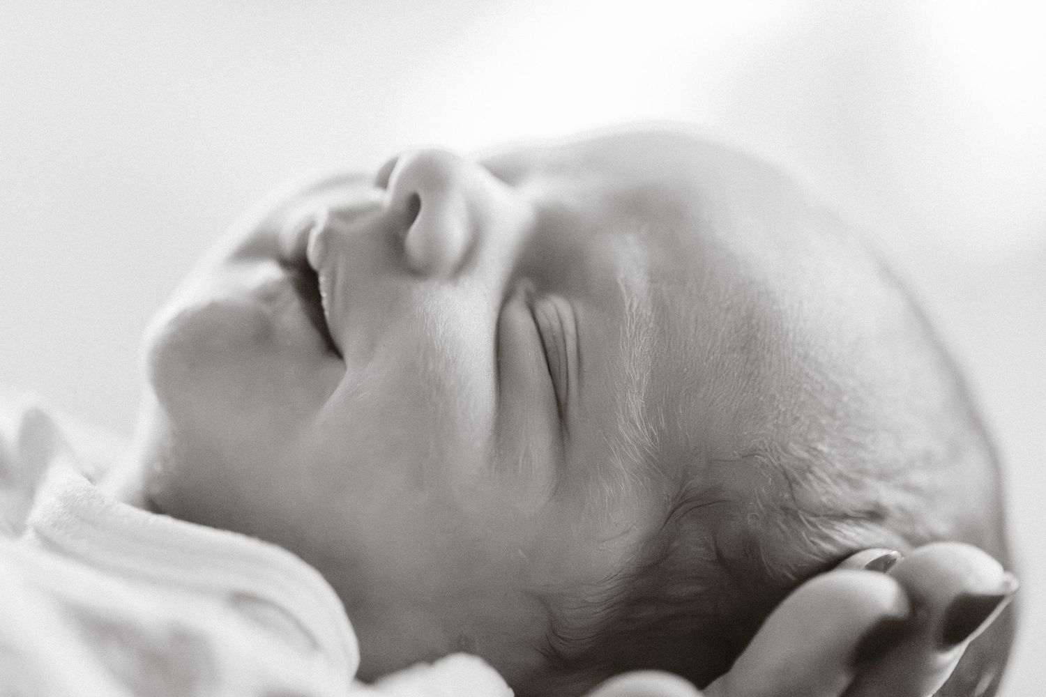 Black and white close-up portrait of a peaceful sleeping newborn baby's face and profile.