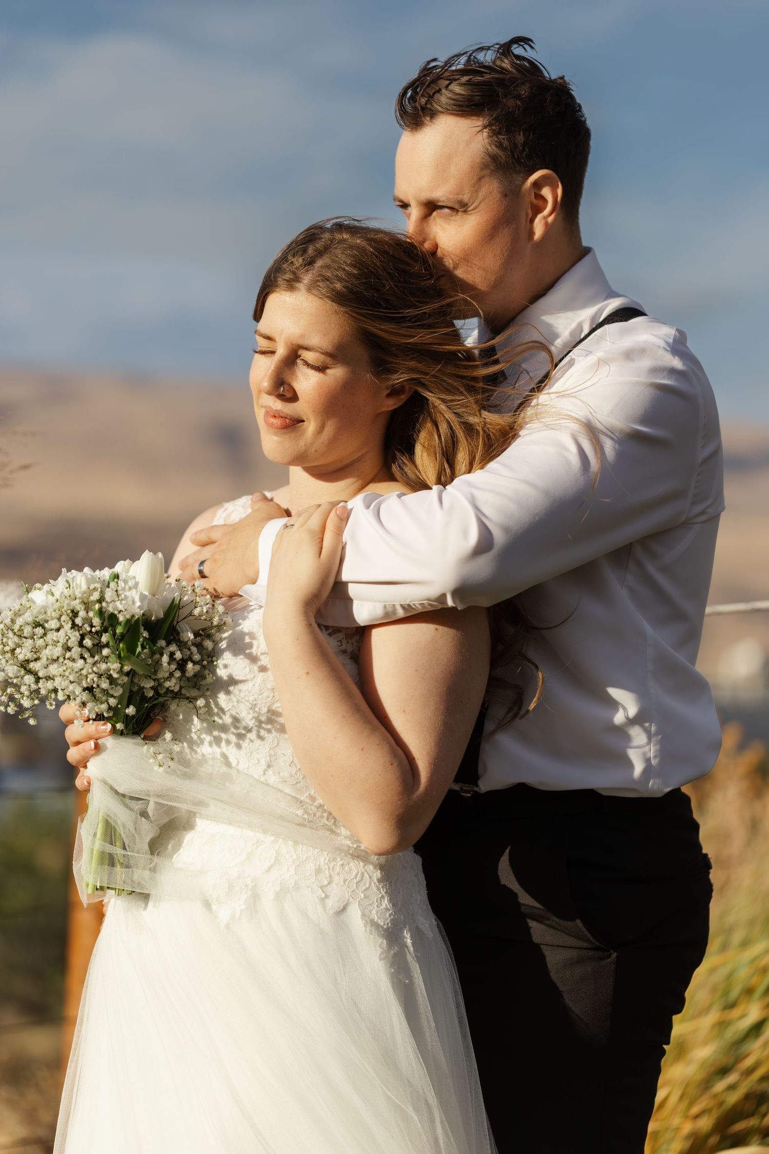 A couple embraces during their wedding photoshoot in a scenic outdoor setting.