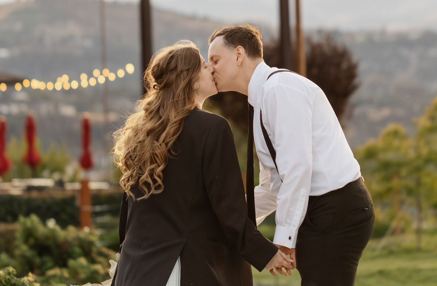Wedding celebration at sunset with string lights glowing in an outdoor venue.
