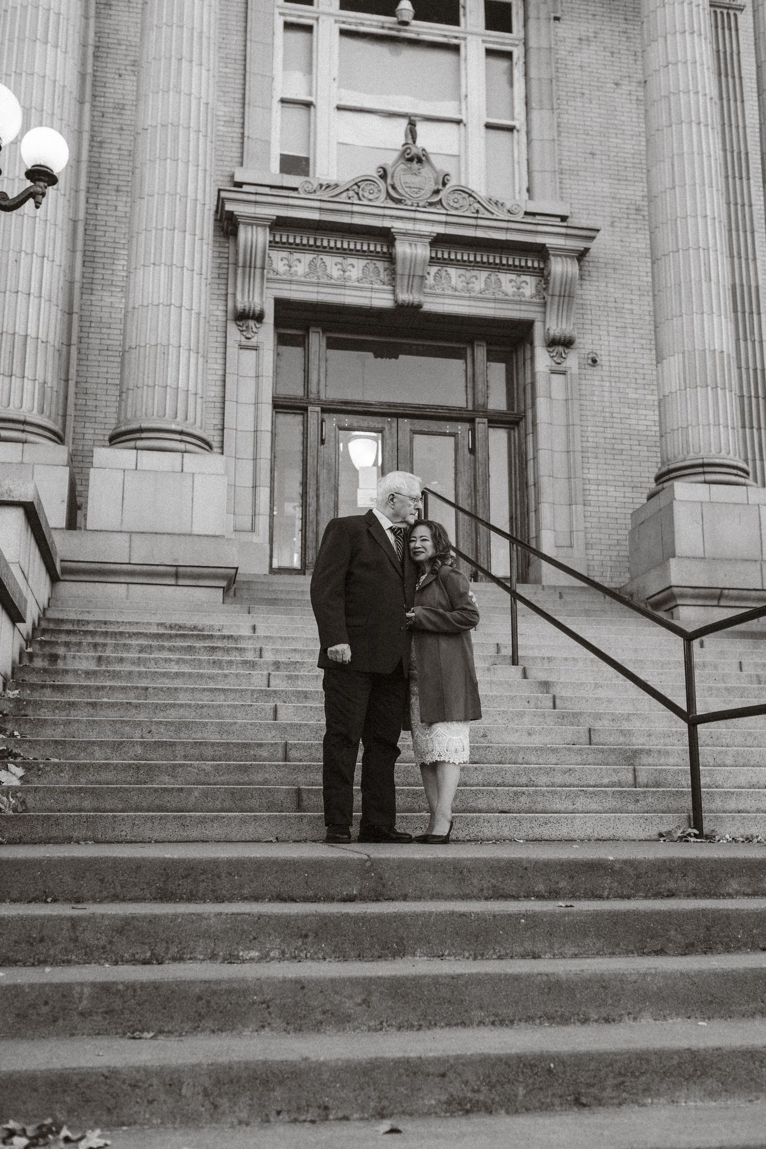 A black and white photo showing people standing on the steps of a neoclassical building with columns.