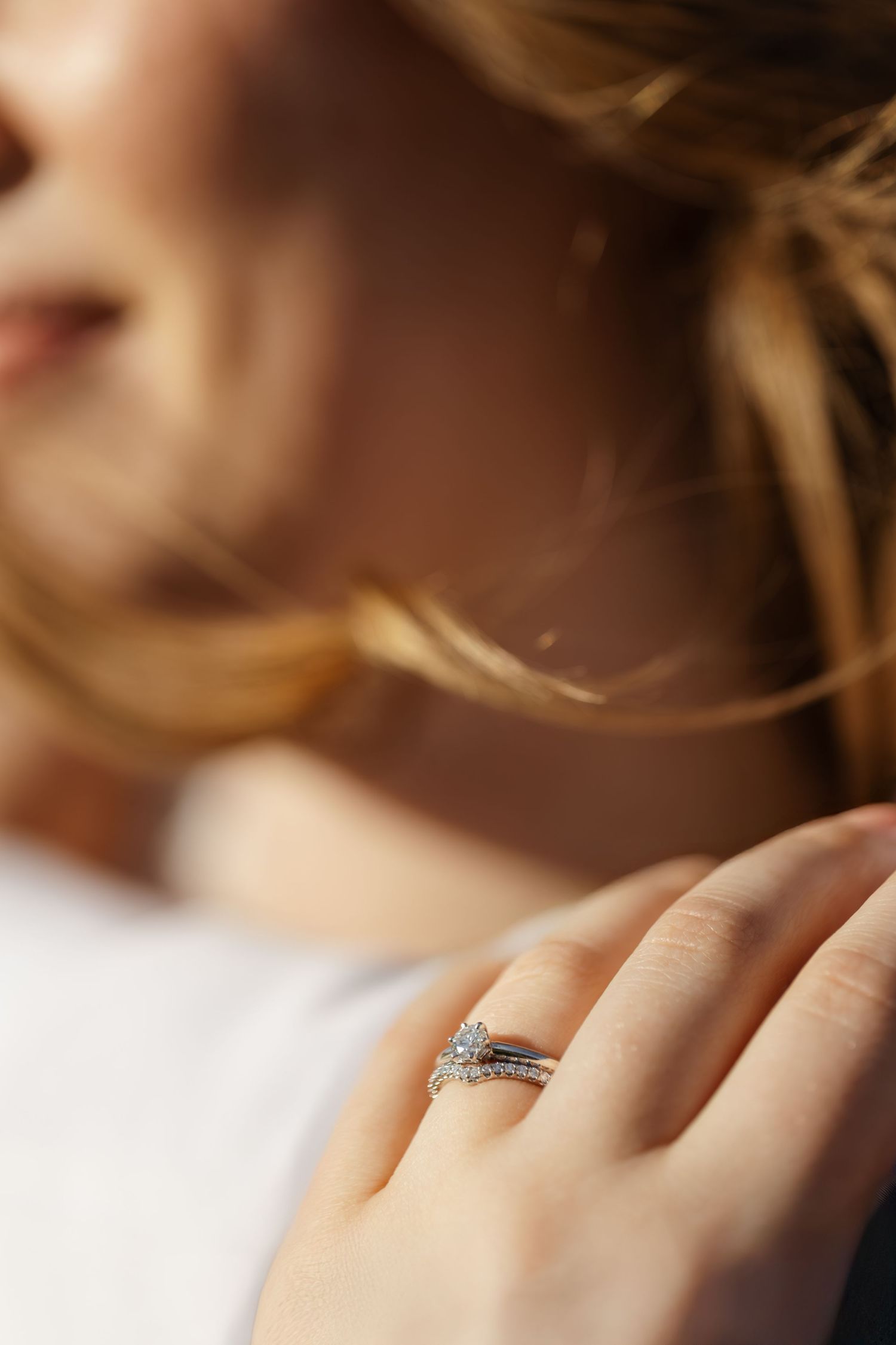 Close-up shot of a sparkling engagement ring on a hand against a soft blurred background.