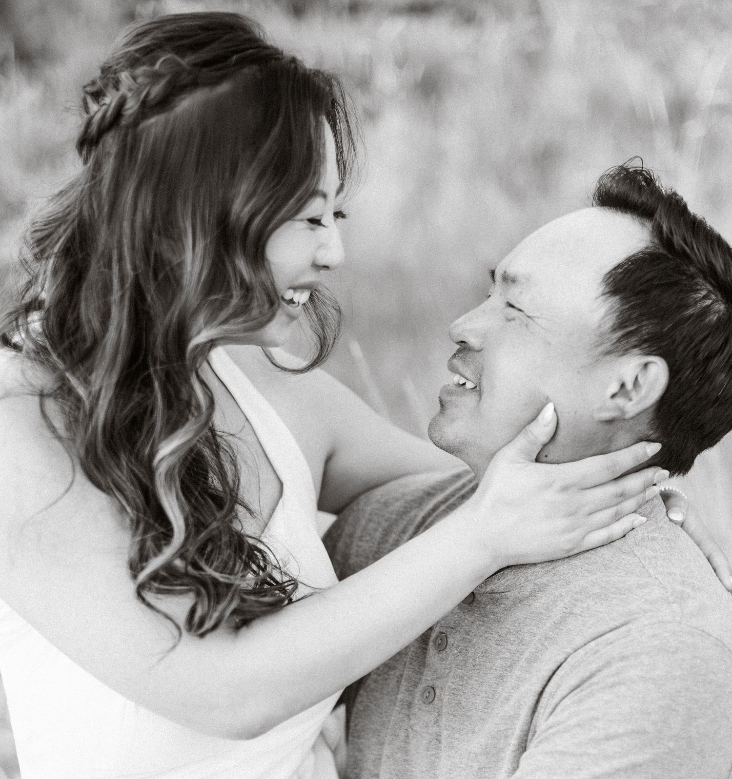 Intimate black and white portrait of a couple sharing tender moments outdoors.