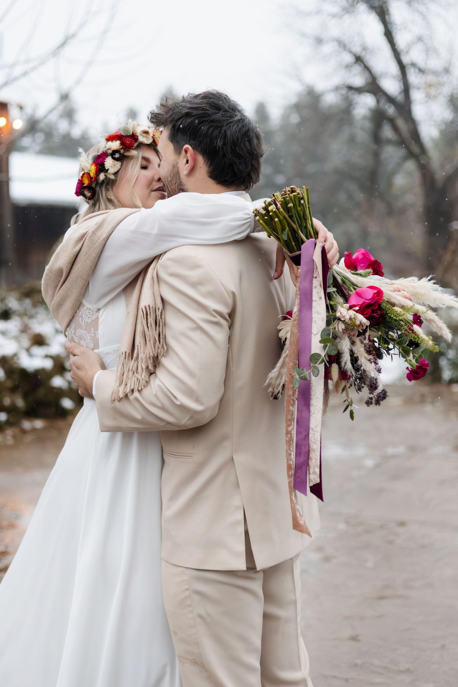 Winter wedding scene with floral bouquet and flowing ribbons in snowy setting.