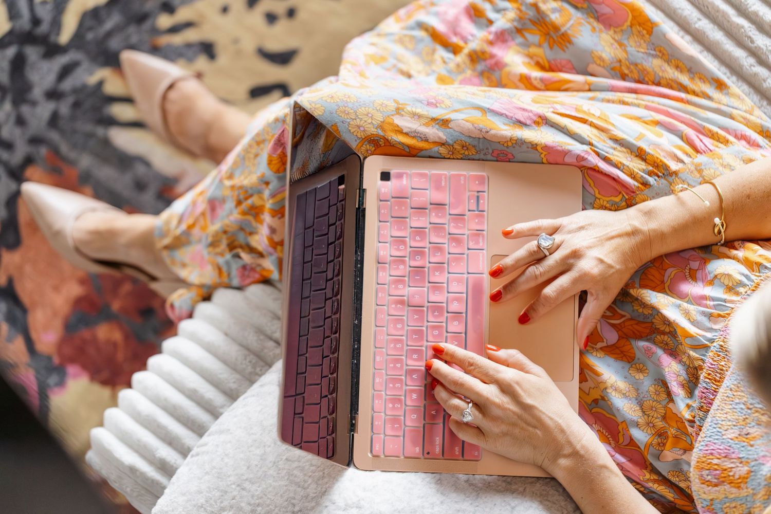 Hands typing on a pink keyboard with floral pattern overlay.