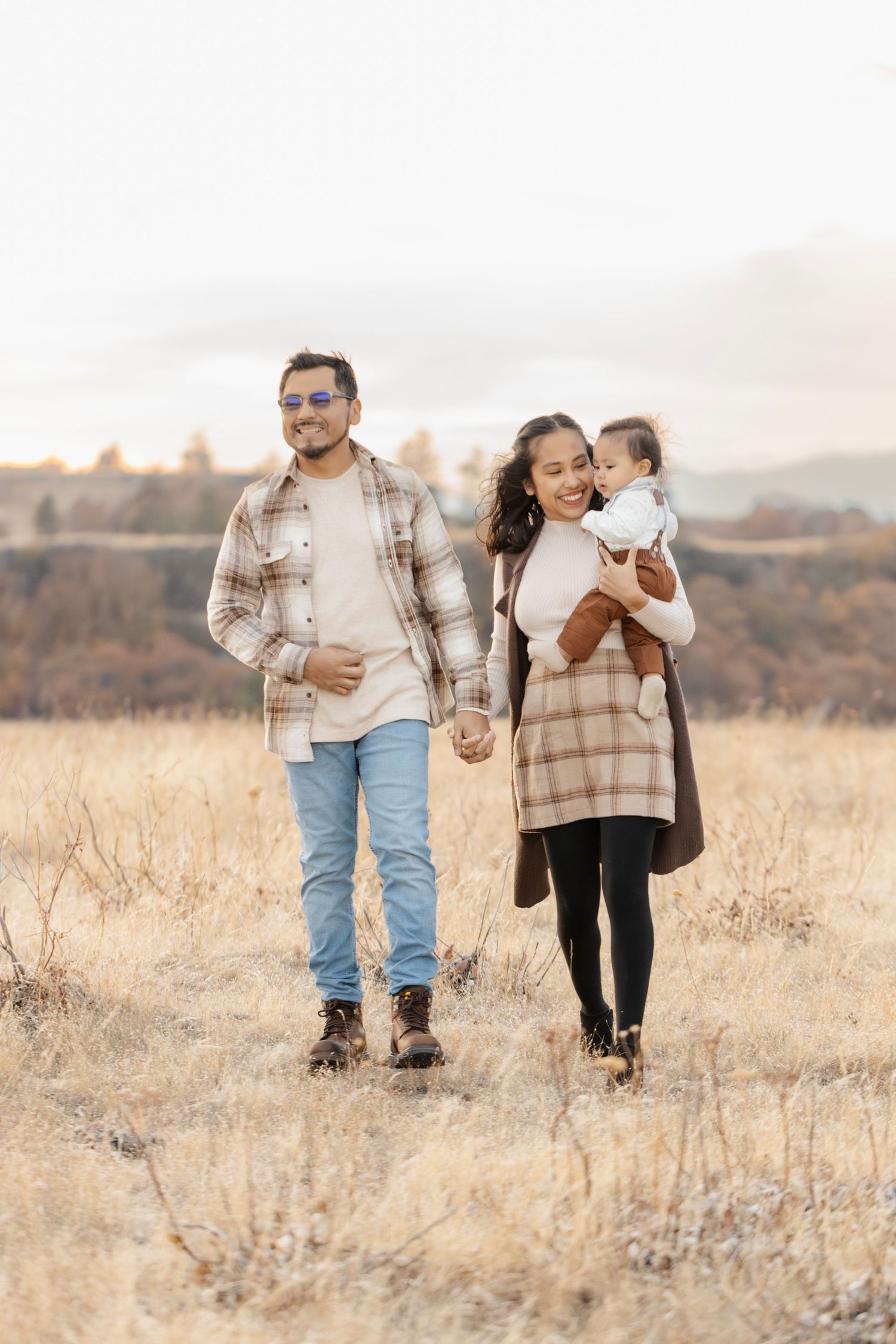 Family walking together through golden autumn field at sunset.