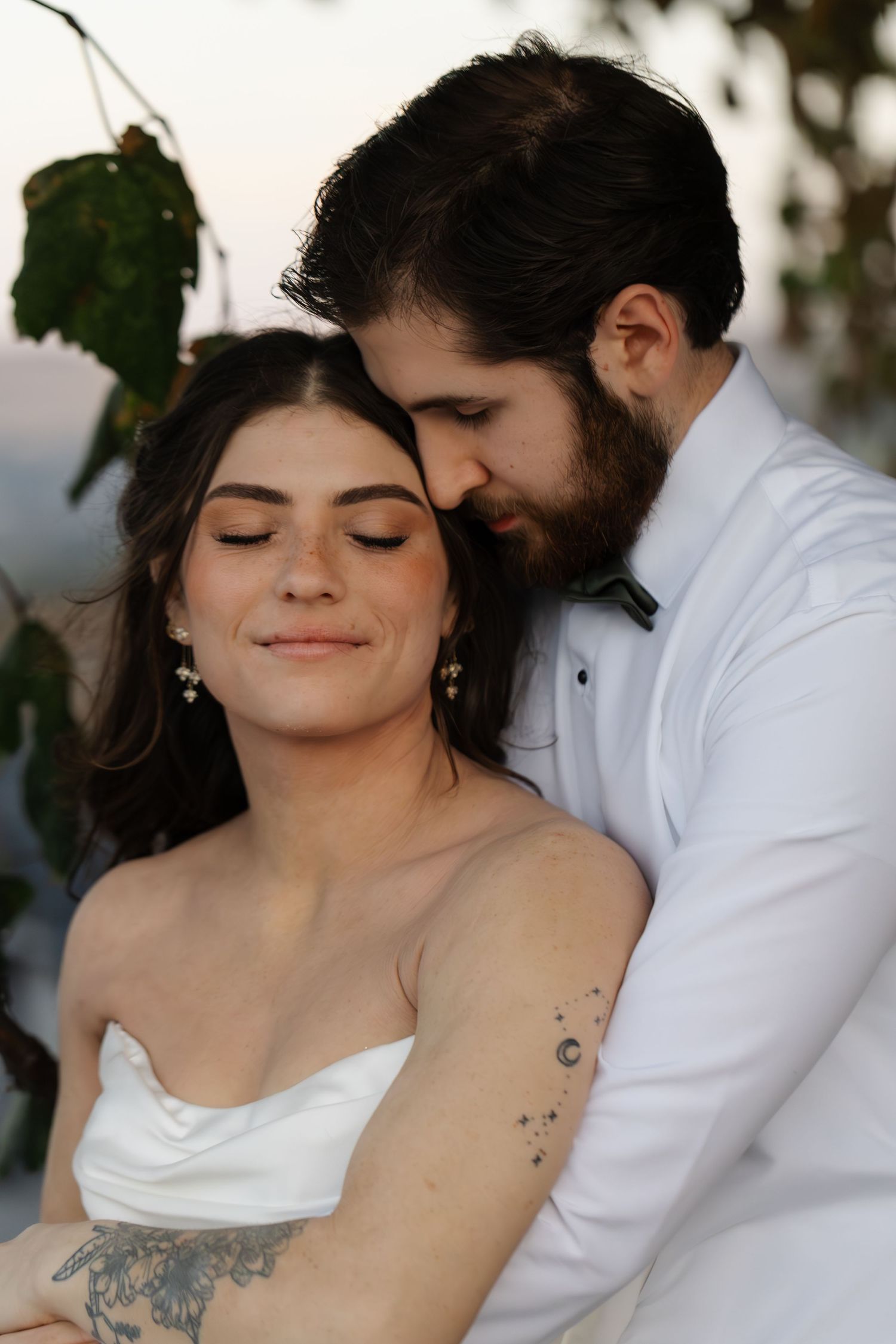 Romantic close-up wedding photos showing a couple embracing with visible tattoos and intimate moments.