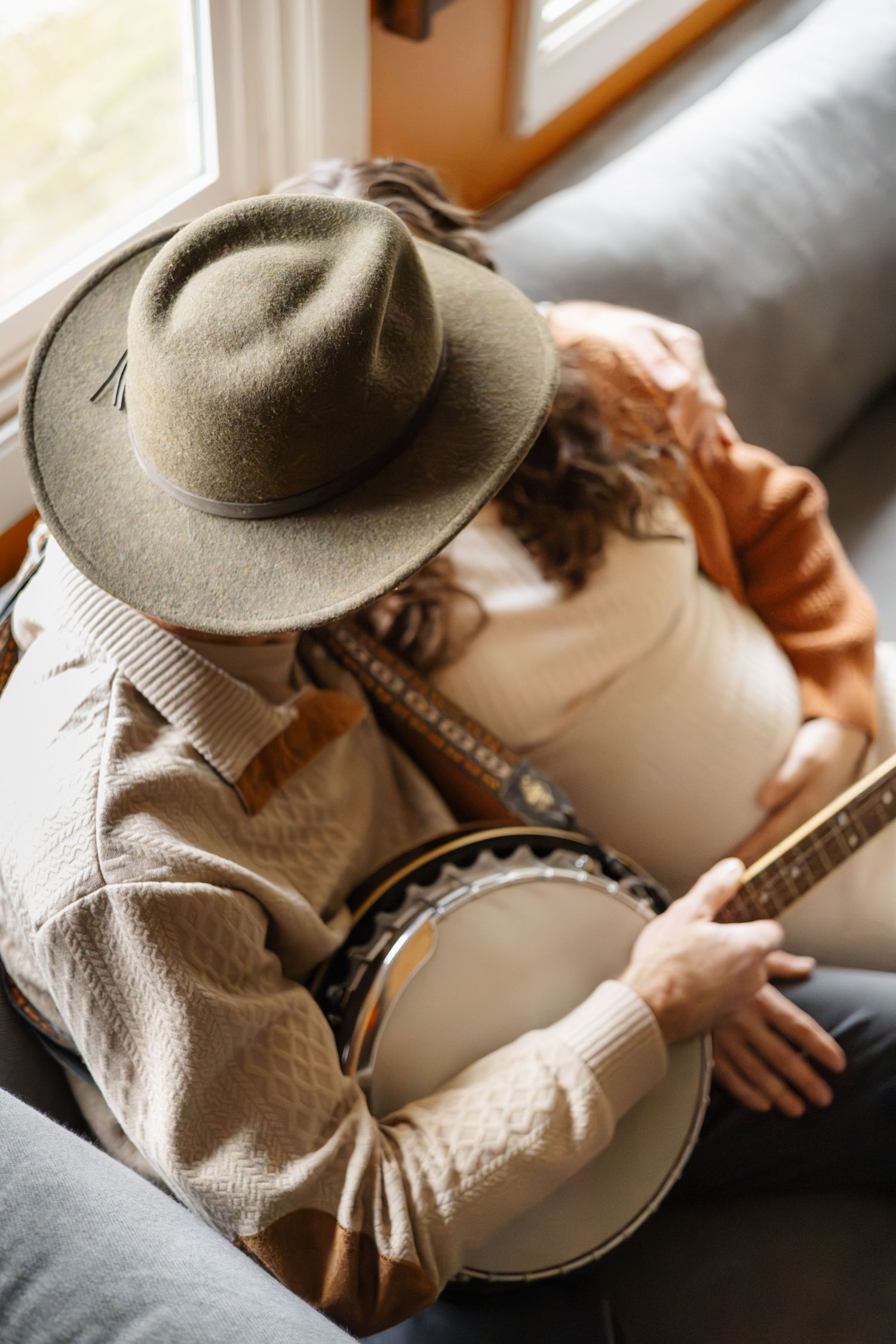 Cozy indoor scene with musician playing banjo while wearing cowboy hat.