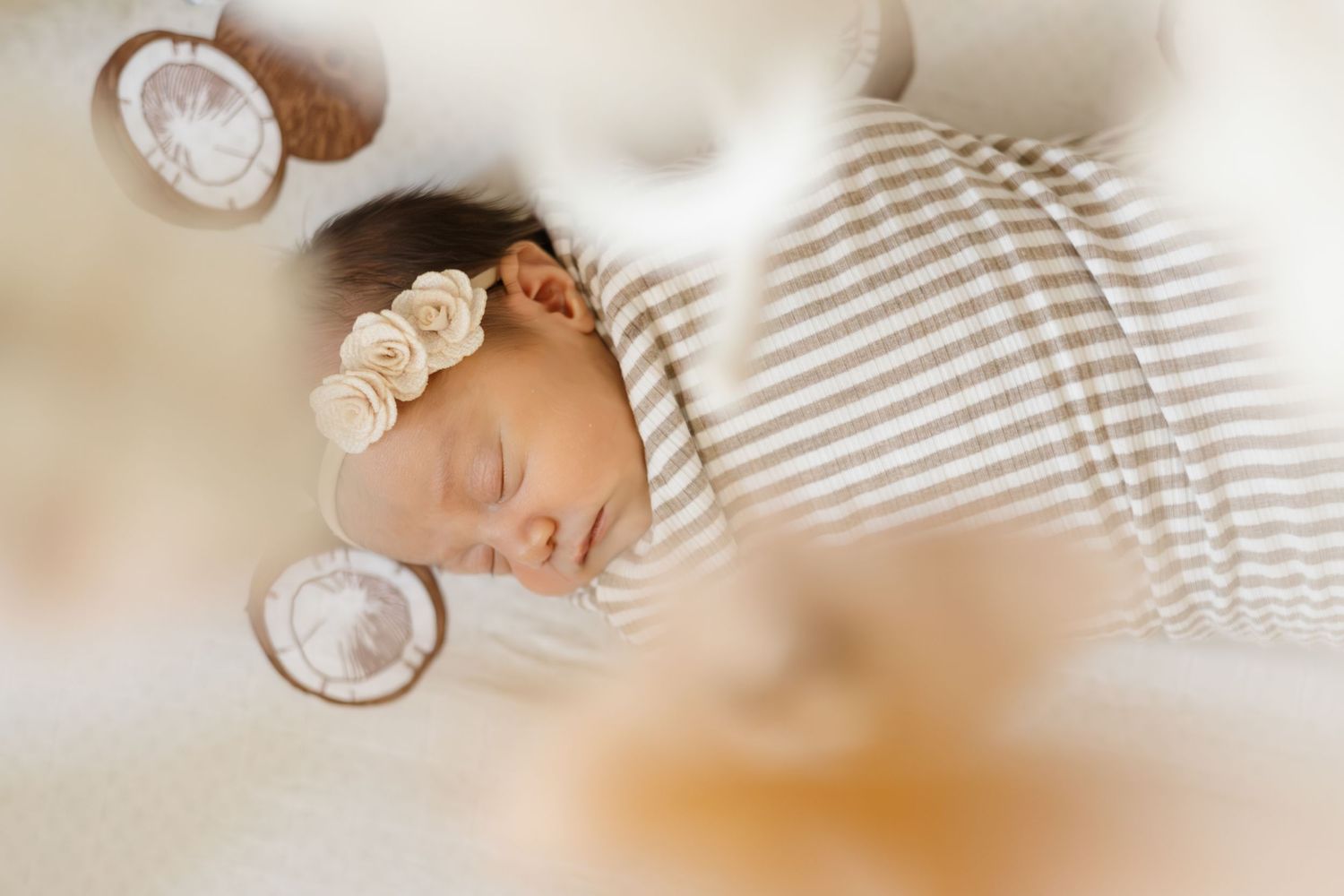 Peaceful sleeping newborn swaddled in soft striped fabric with delicate lighting.