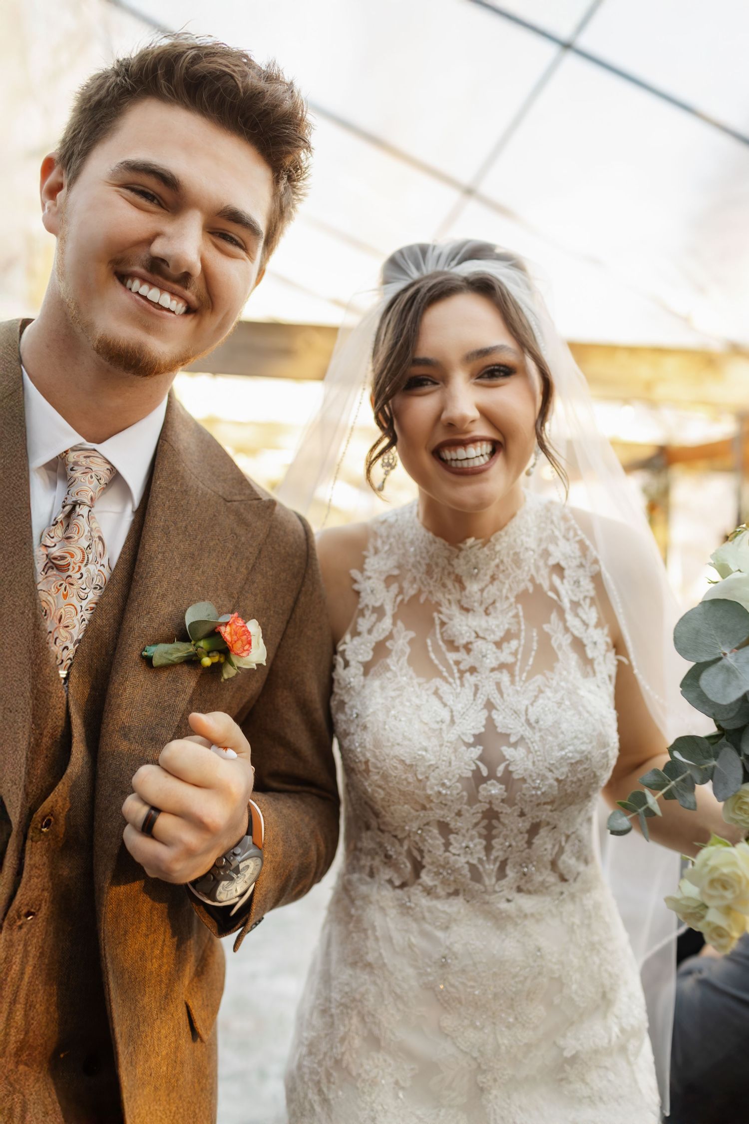 Newlyweds share a joyful moment together under a tent at their wedding celebration.