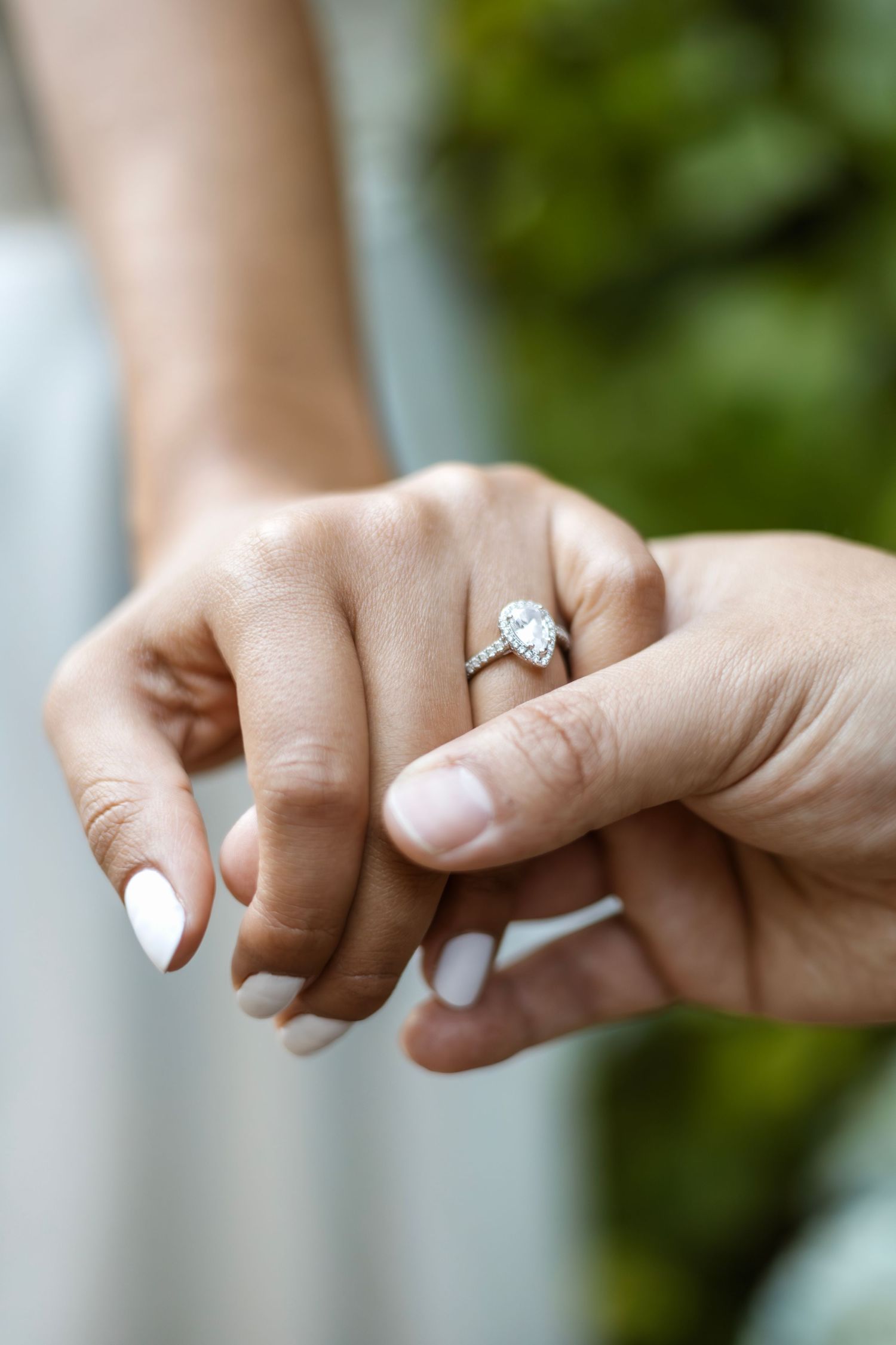 Detail shot of hands with engagement ring showing delicate diamond solitaire.
