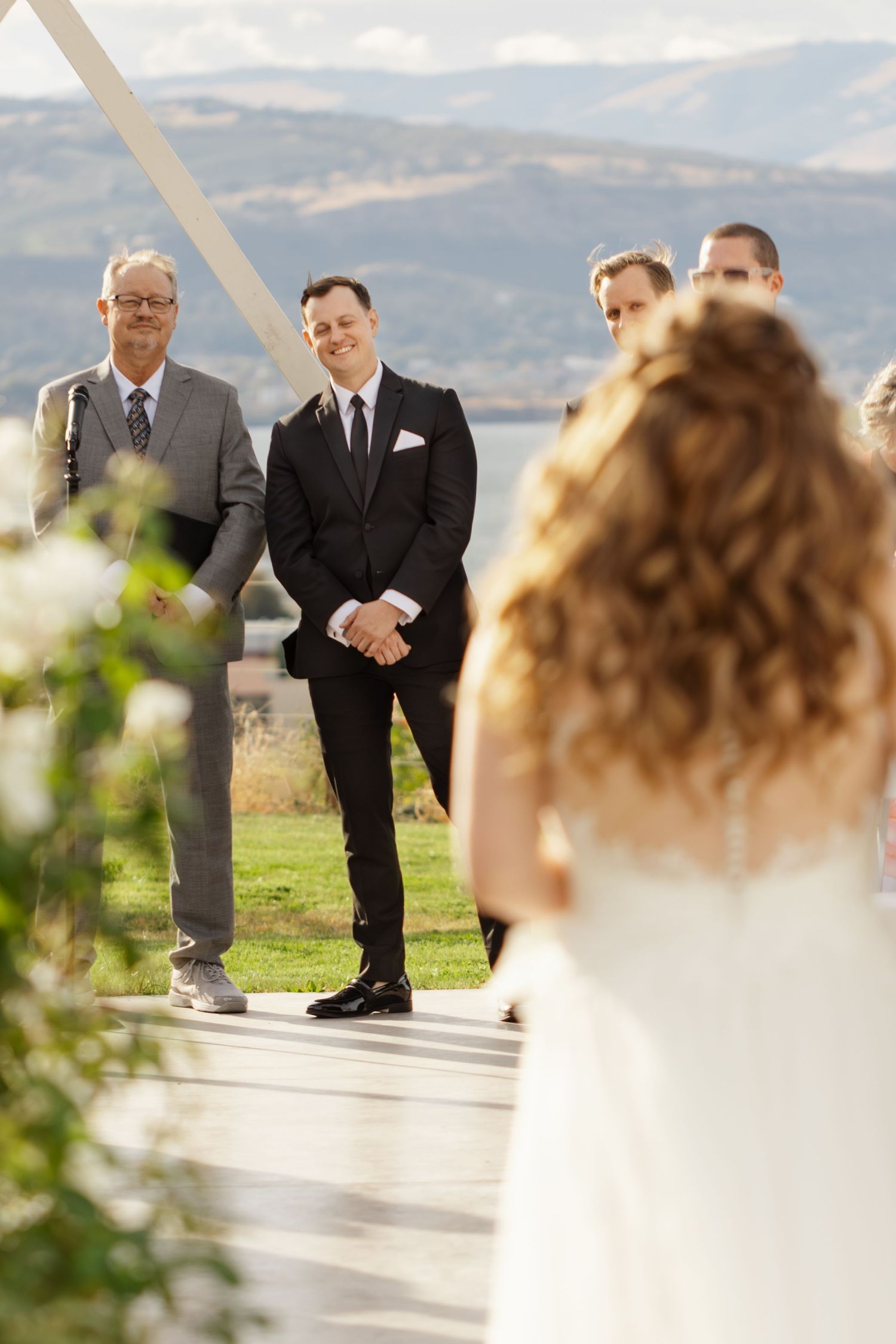 Newlyweds share joyful moments during their outdoor wedding ceremony against a scenic mountain backdrop.