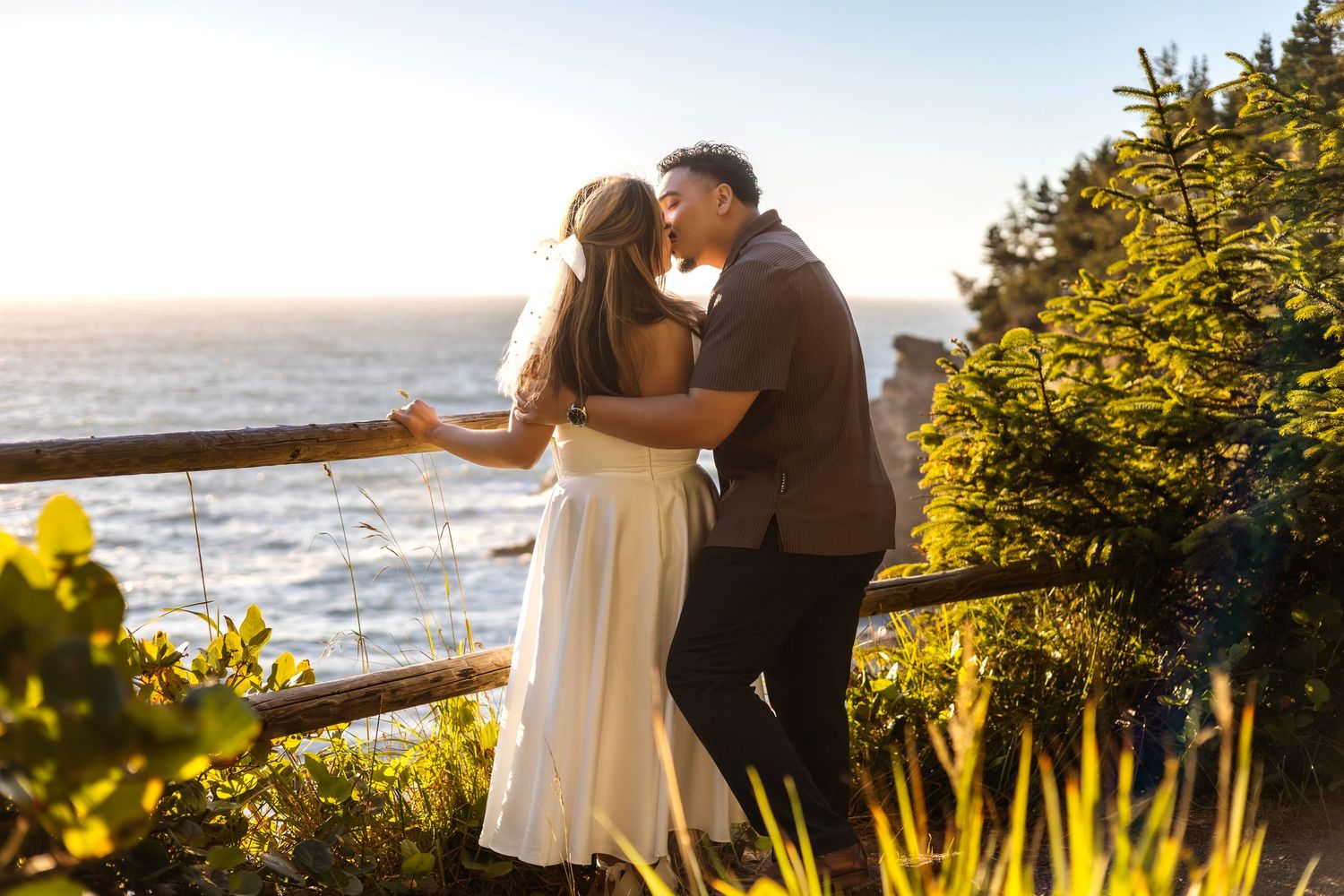 Scenic coastal engagement photos with ocean views and golden sunlight through trees.