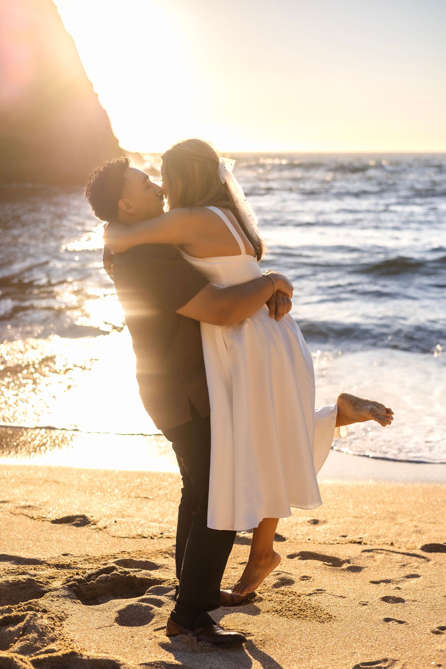 Intimate beach moment captured during golden hour with waves and sand in background.
