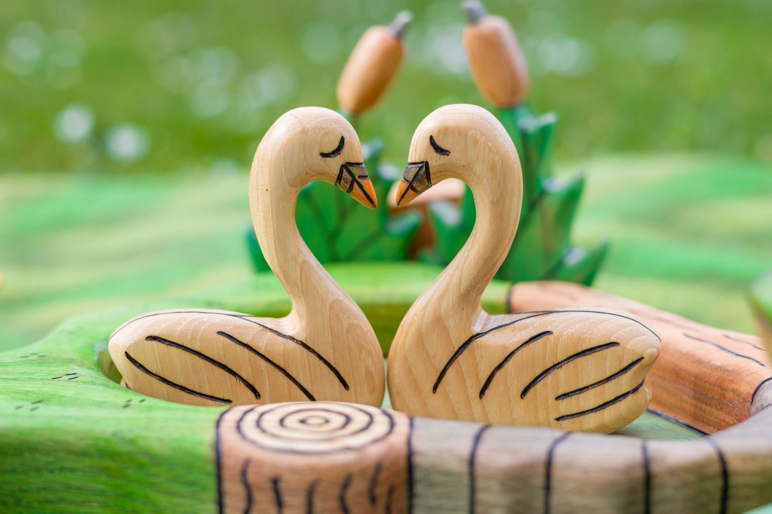 Wooden swan decorations with painted details on a green background.