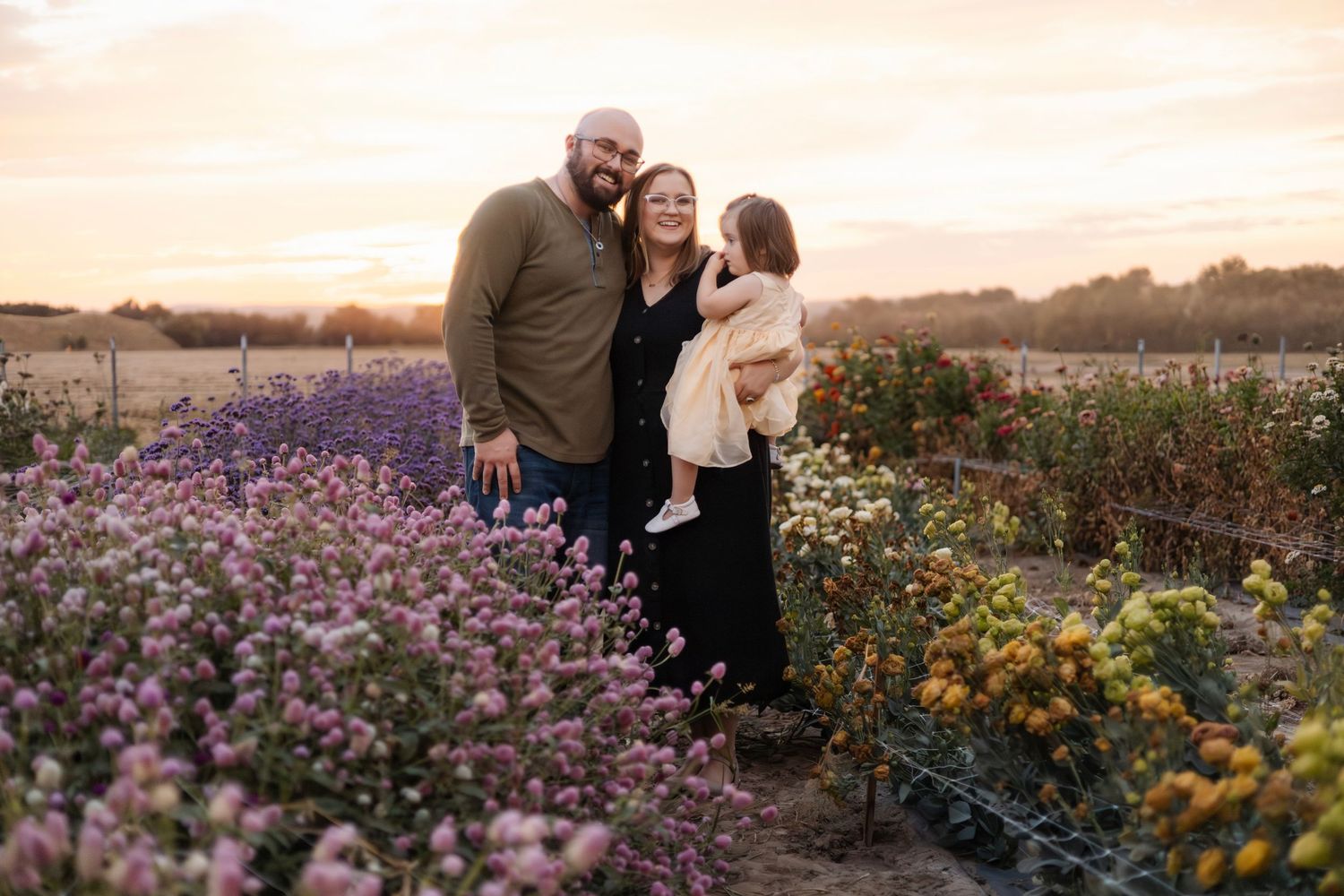 Family enjoying sunset in a field of purple wildflowers.