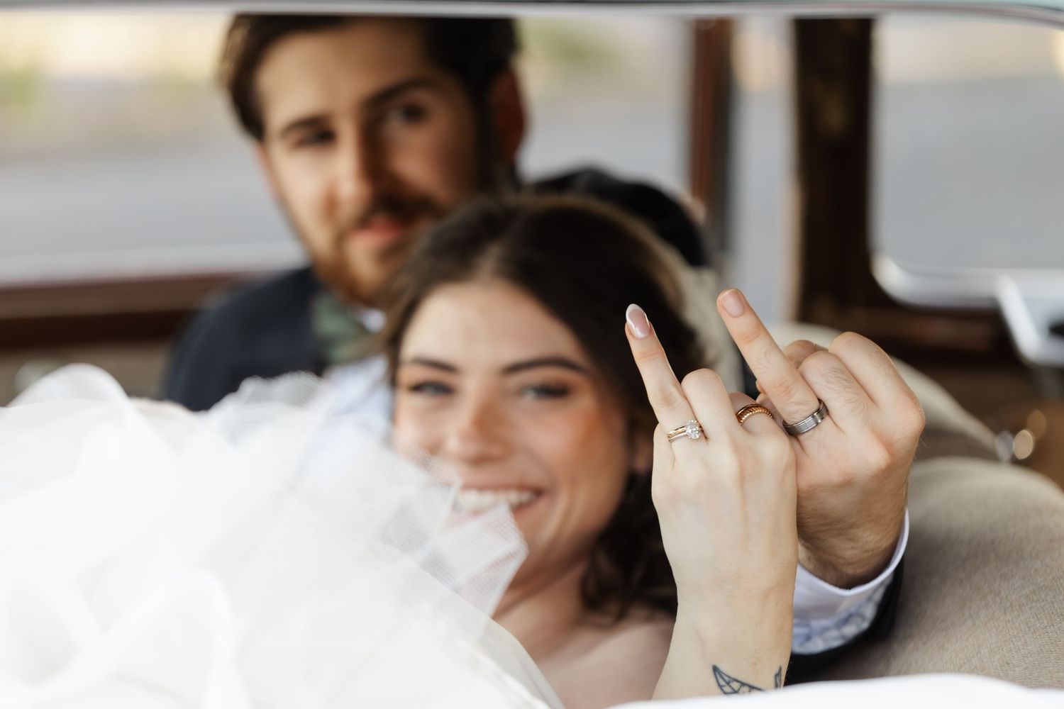 Joyful wedding party laughs together while taking candid photos indoors.