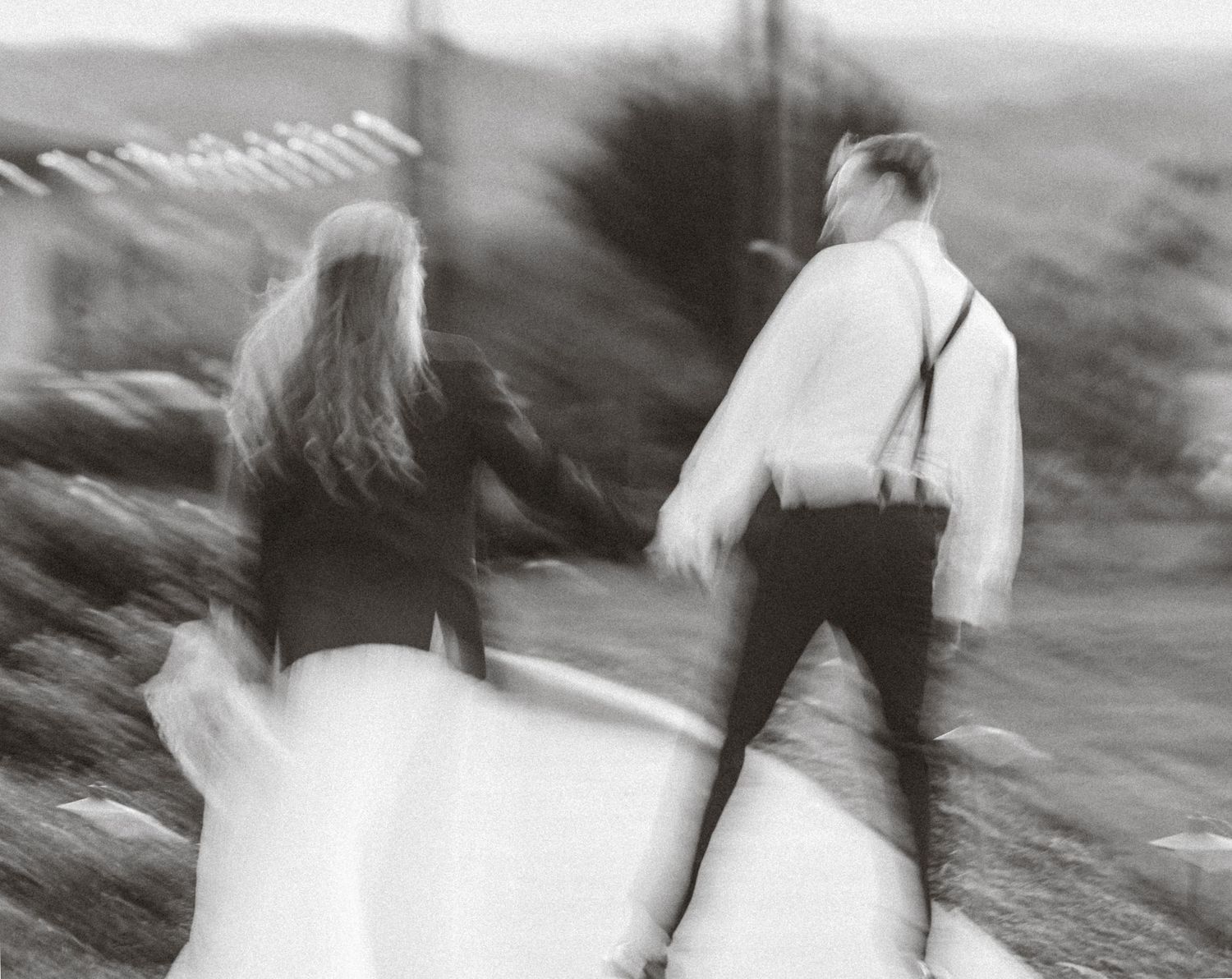 Black and white motion blur photograph of wedding guests walking outdoors.