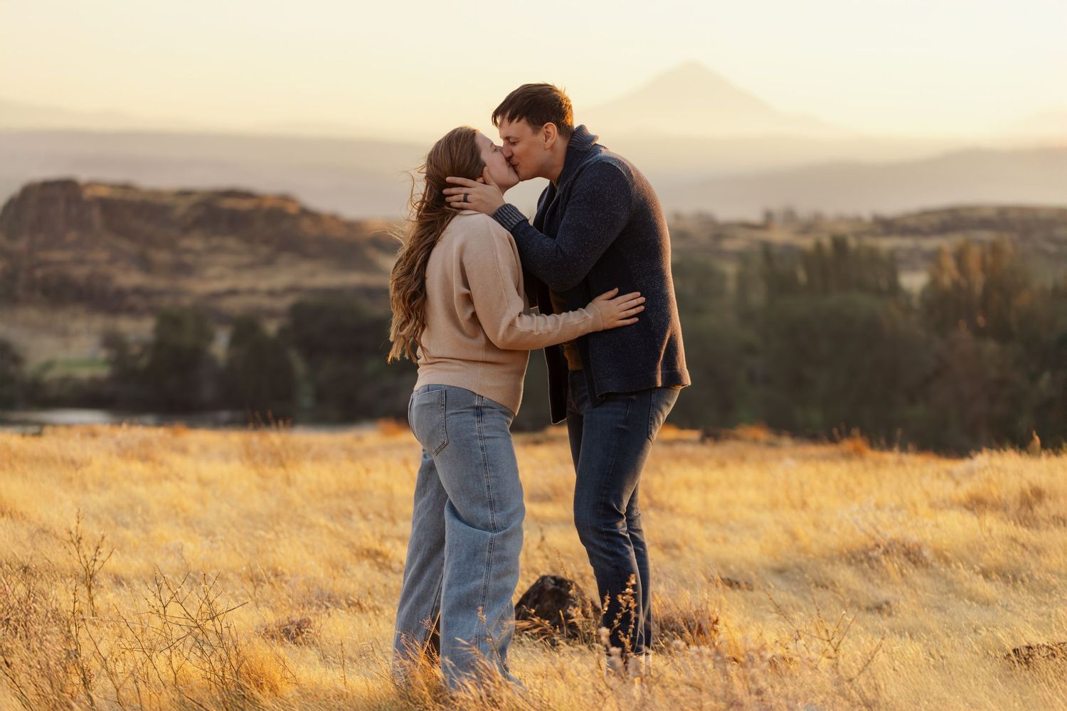 Romantic sunset moment in golden field with mountains in background.