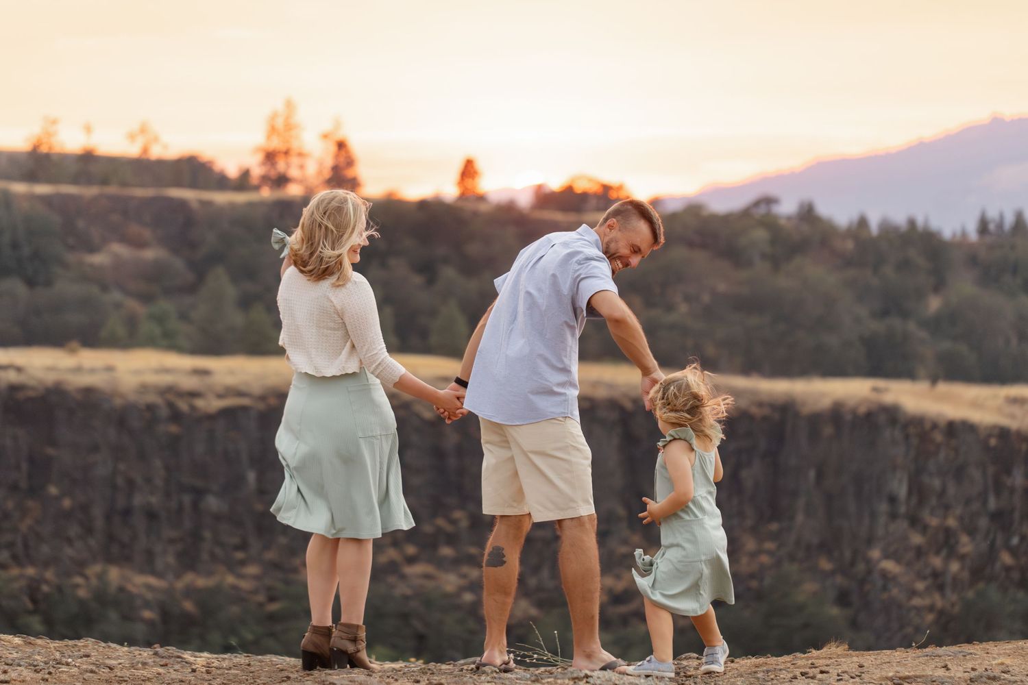 Family walking together on trail during sunset with mountains in background.