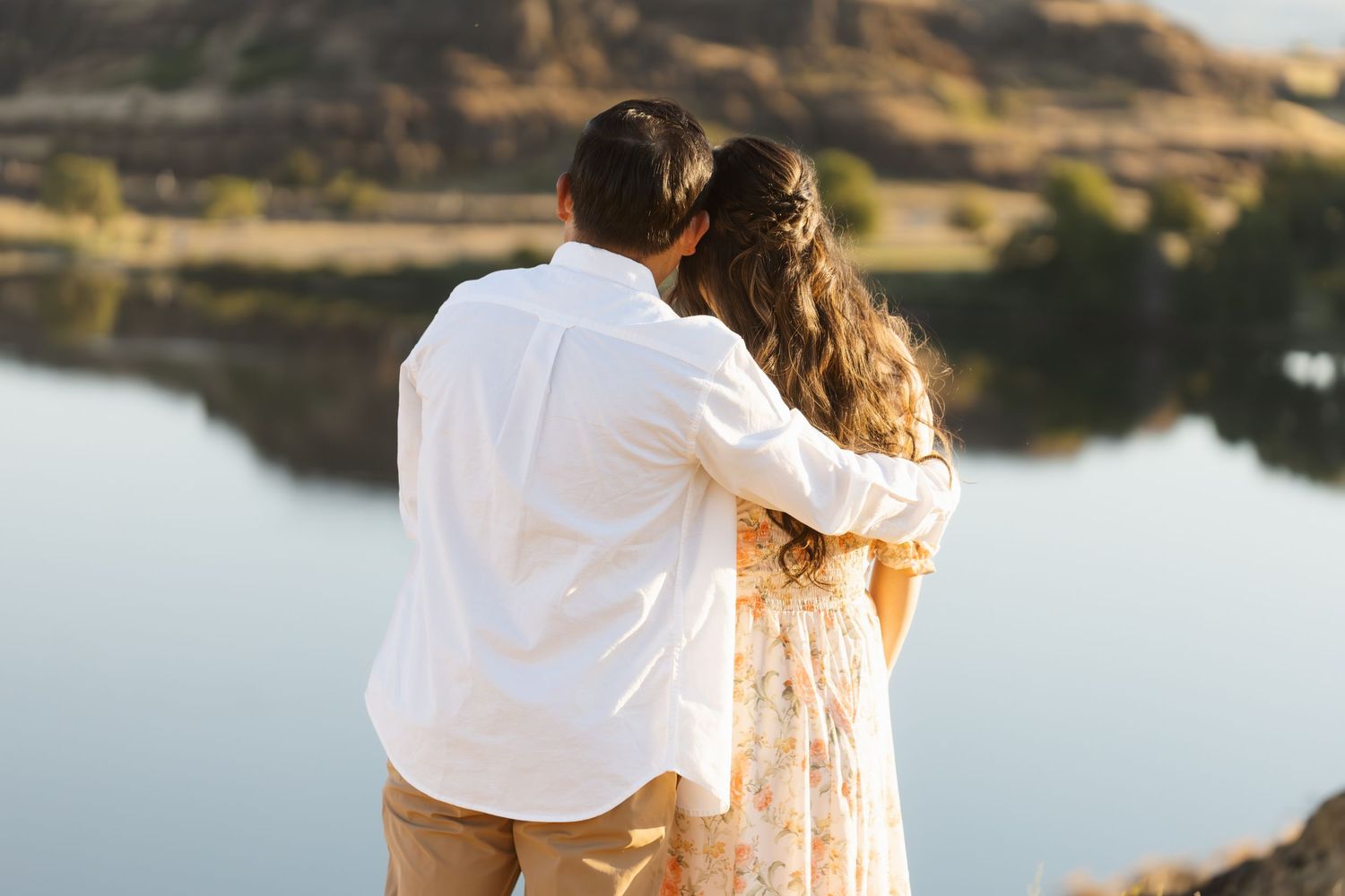 Romantic sunset photoshoot by a serene lake with golden hour lighting.