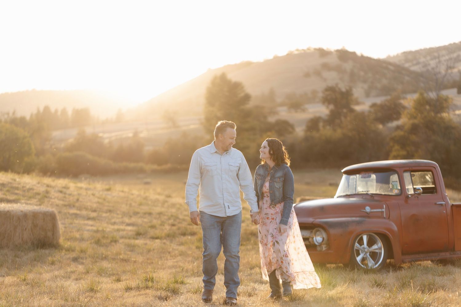 A romantic sunset photoshoot in a field with a classic red truck as a backdrop.