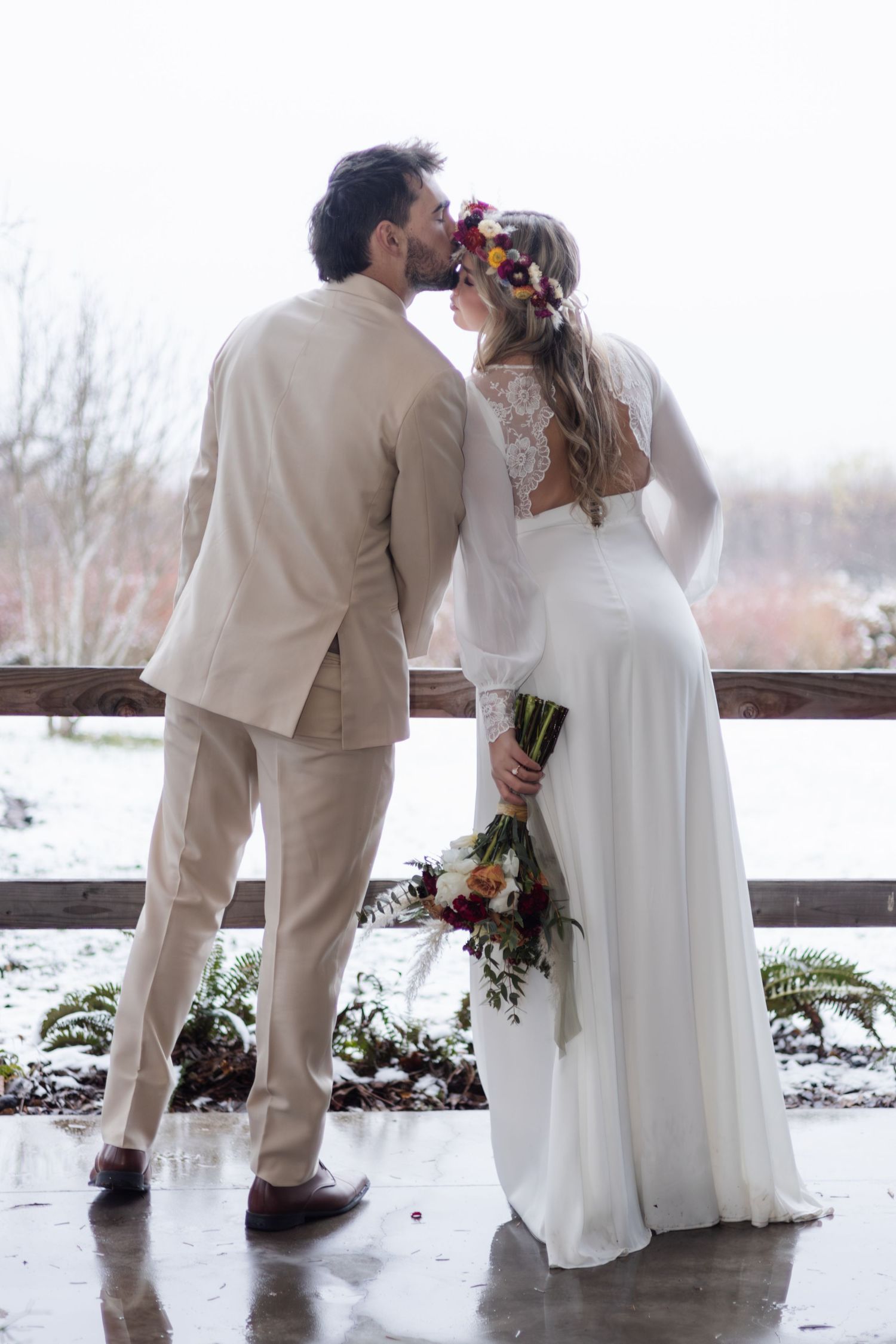 Winter wedding portrait on snowy deck with mountain backdrop.