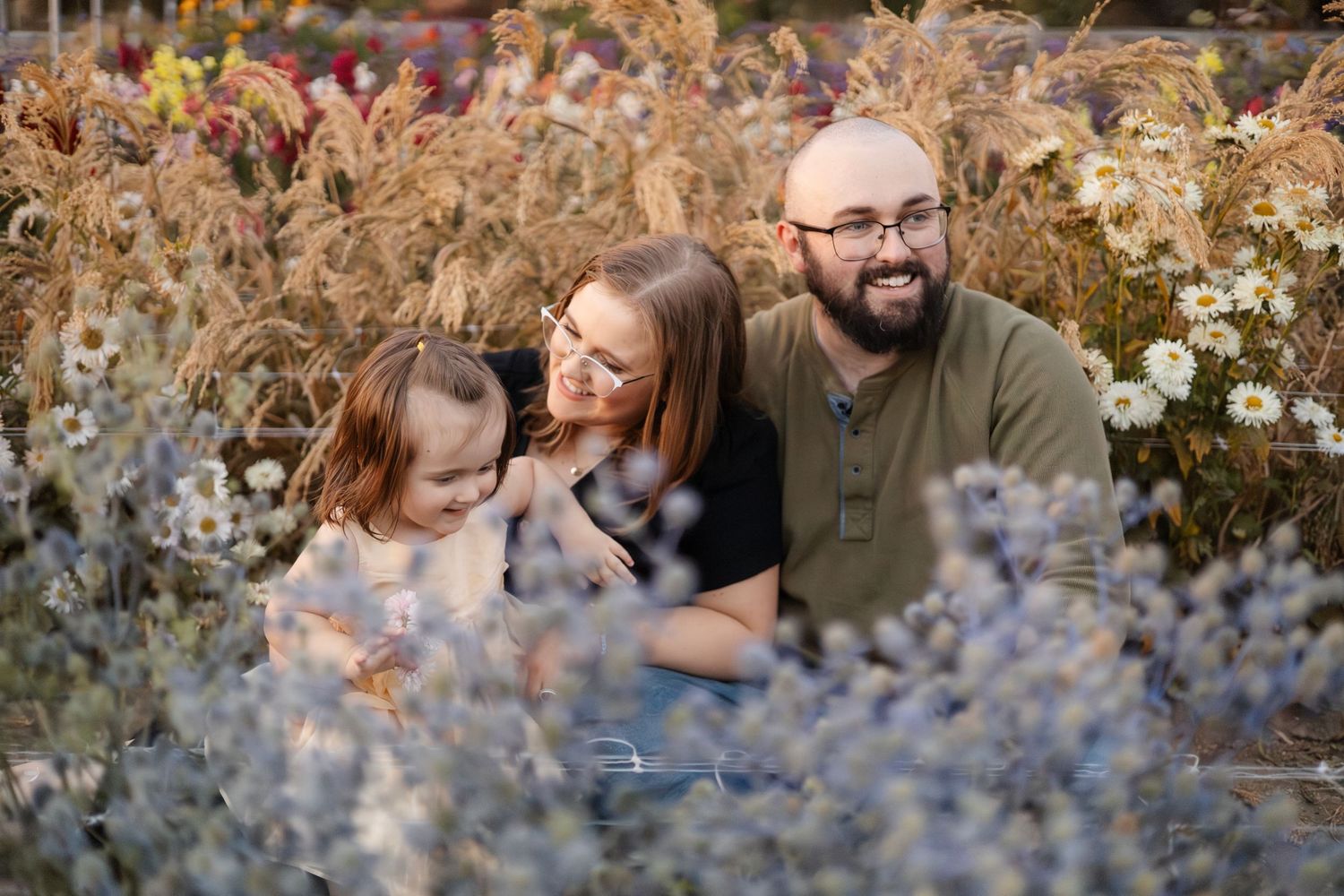 Couple poses among blooming wildflowers in a garden setting.