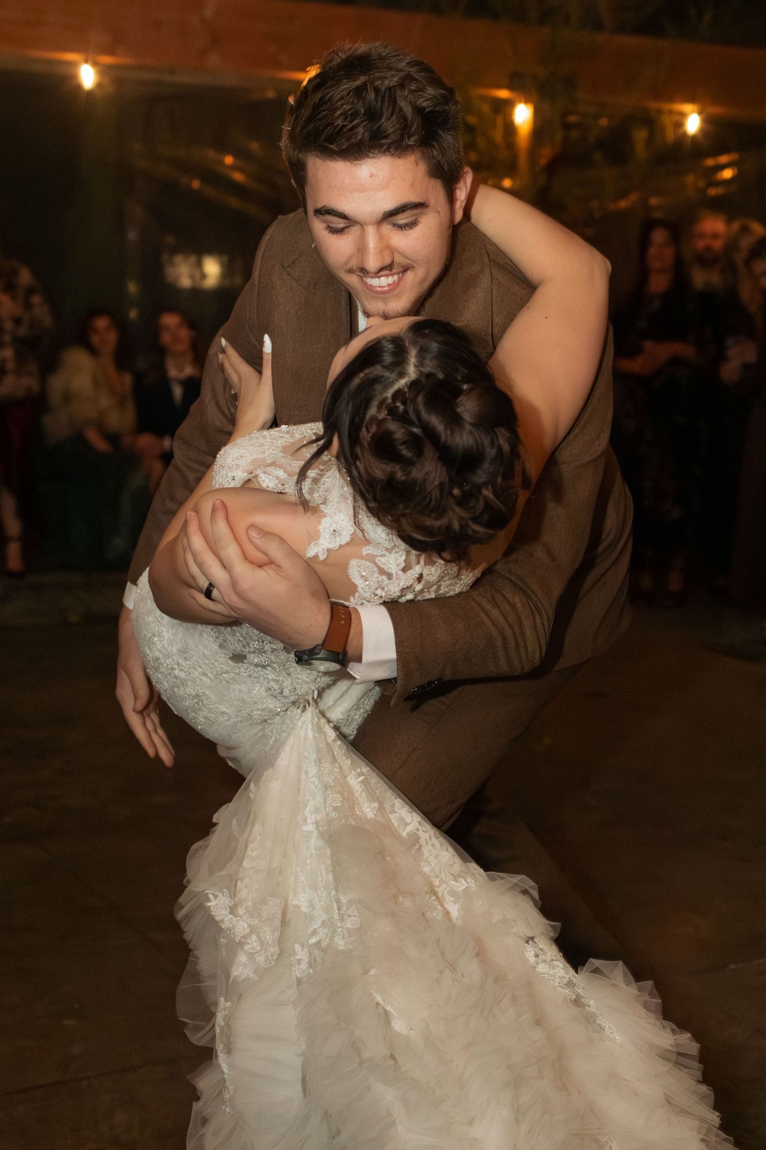 Newlyweds share an intimate dance moment under warm evening lighting at their reception.
