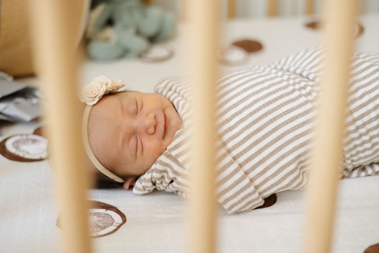 Peaceful newborn sleeping in wooden crib with striped bedding.