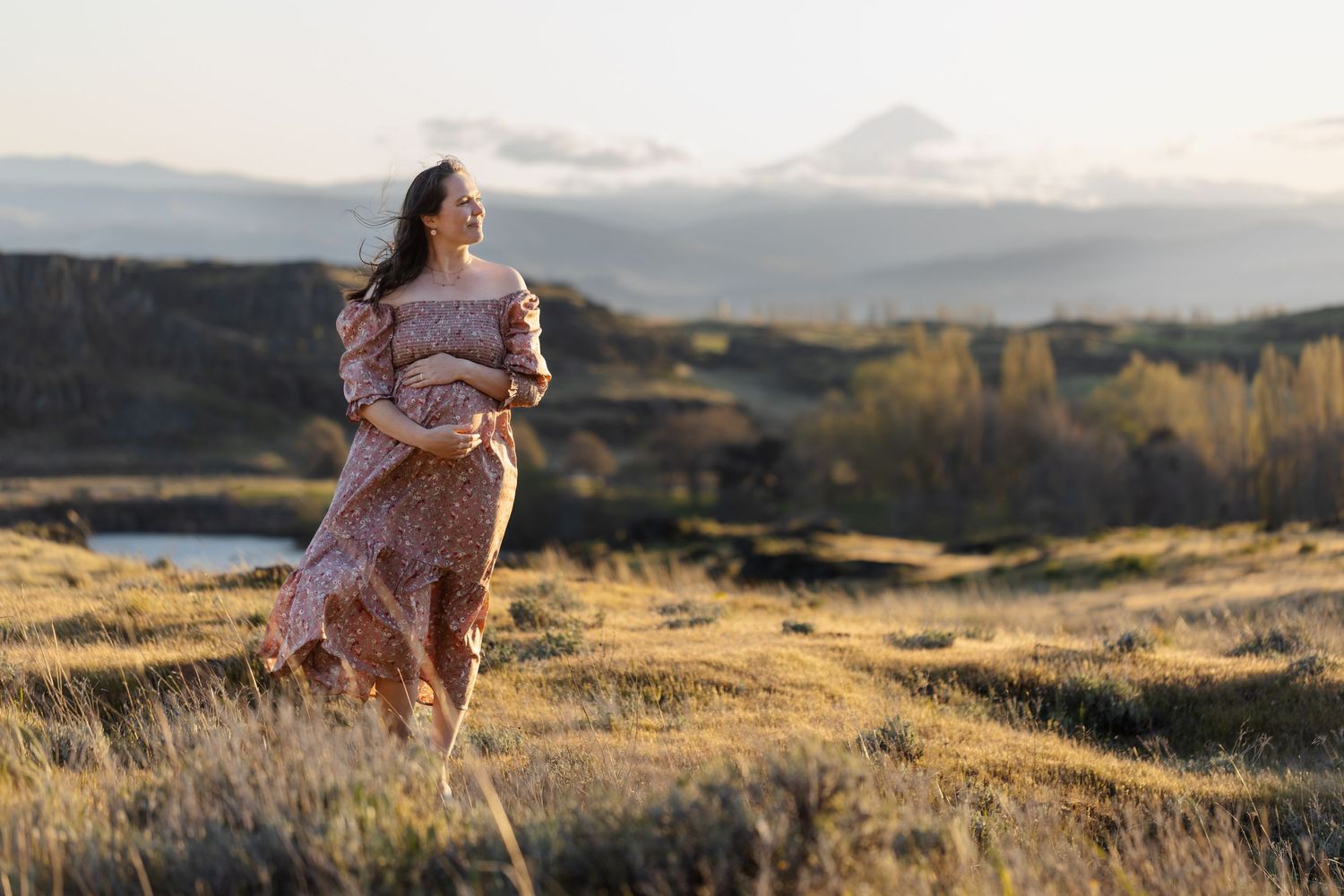 Person in pink dress twirls gracefully on hilltop during golden hour.