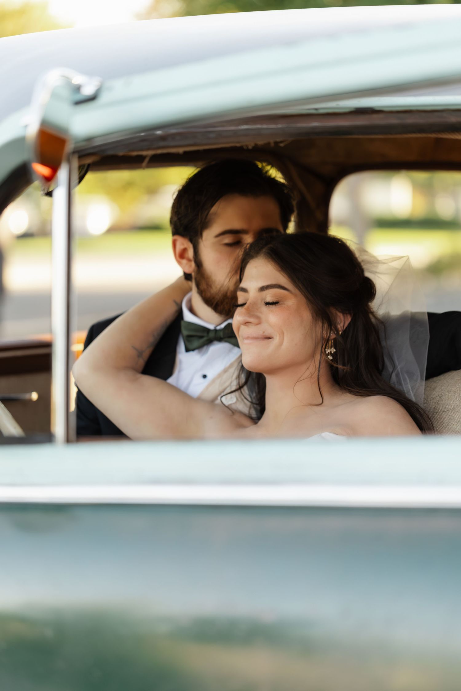 Tender wedding couple sharing romantic moments through car window during their special day.