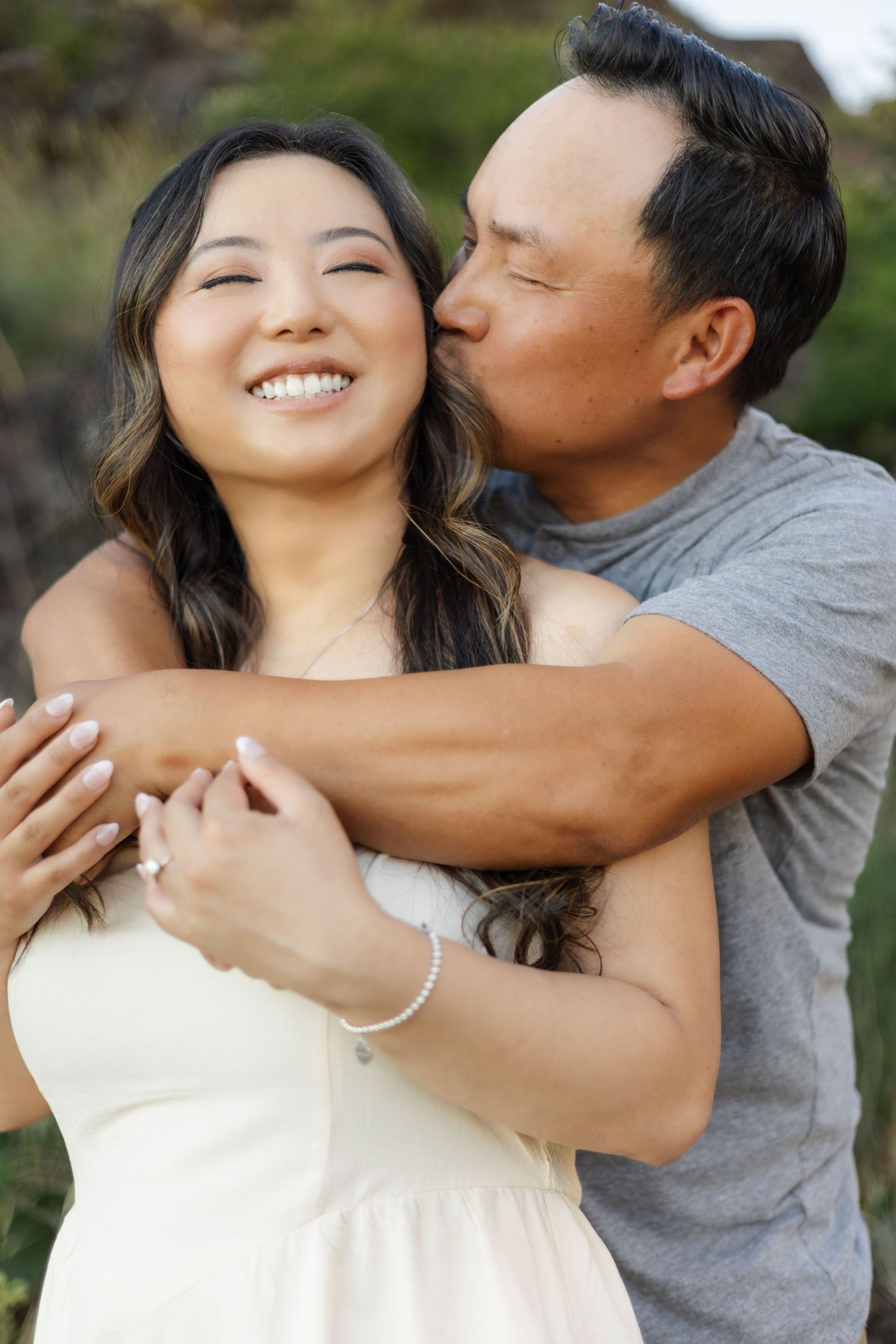 Playful couple embracing and laughing in a natural outdoor setting.