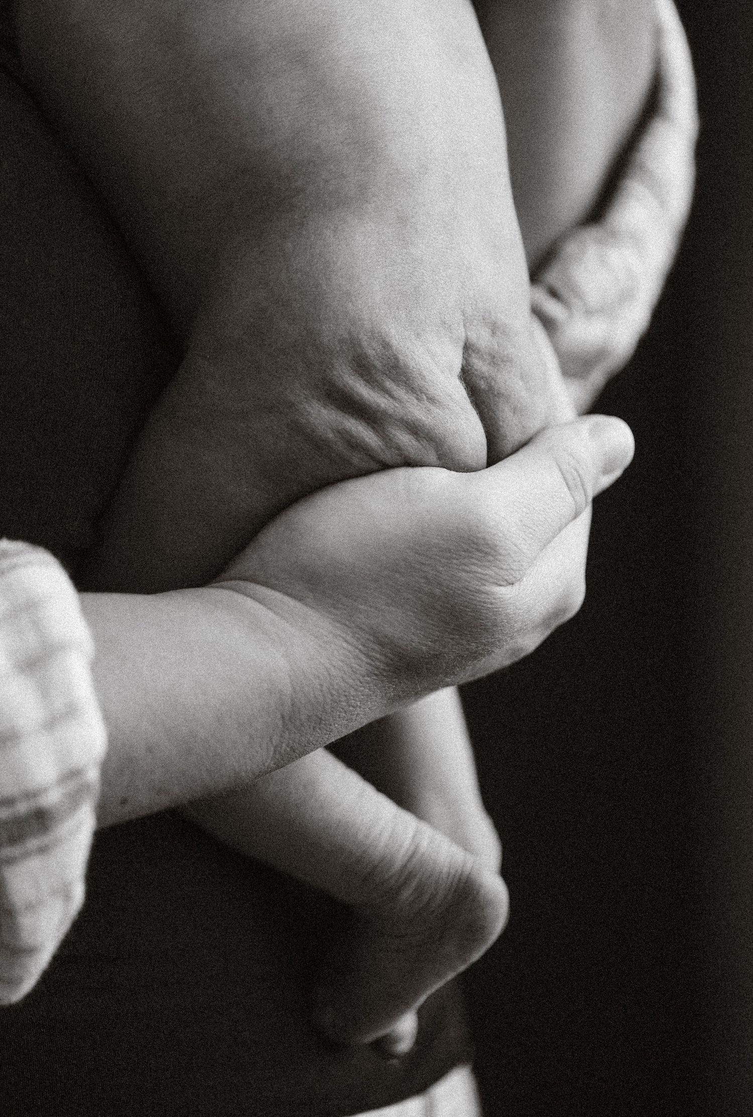 Close-up black and white images of gentle hand gestures against a dark background.