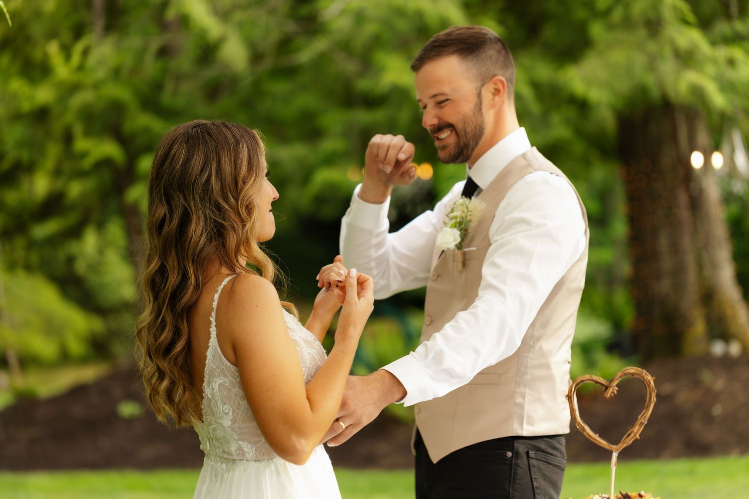 A couple dances together in a romantic outdoor garden setting with lush green foliage in the background.