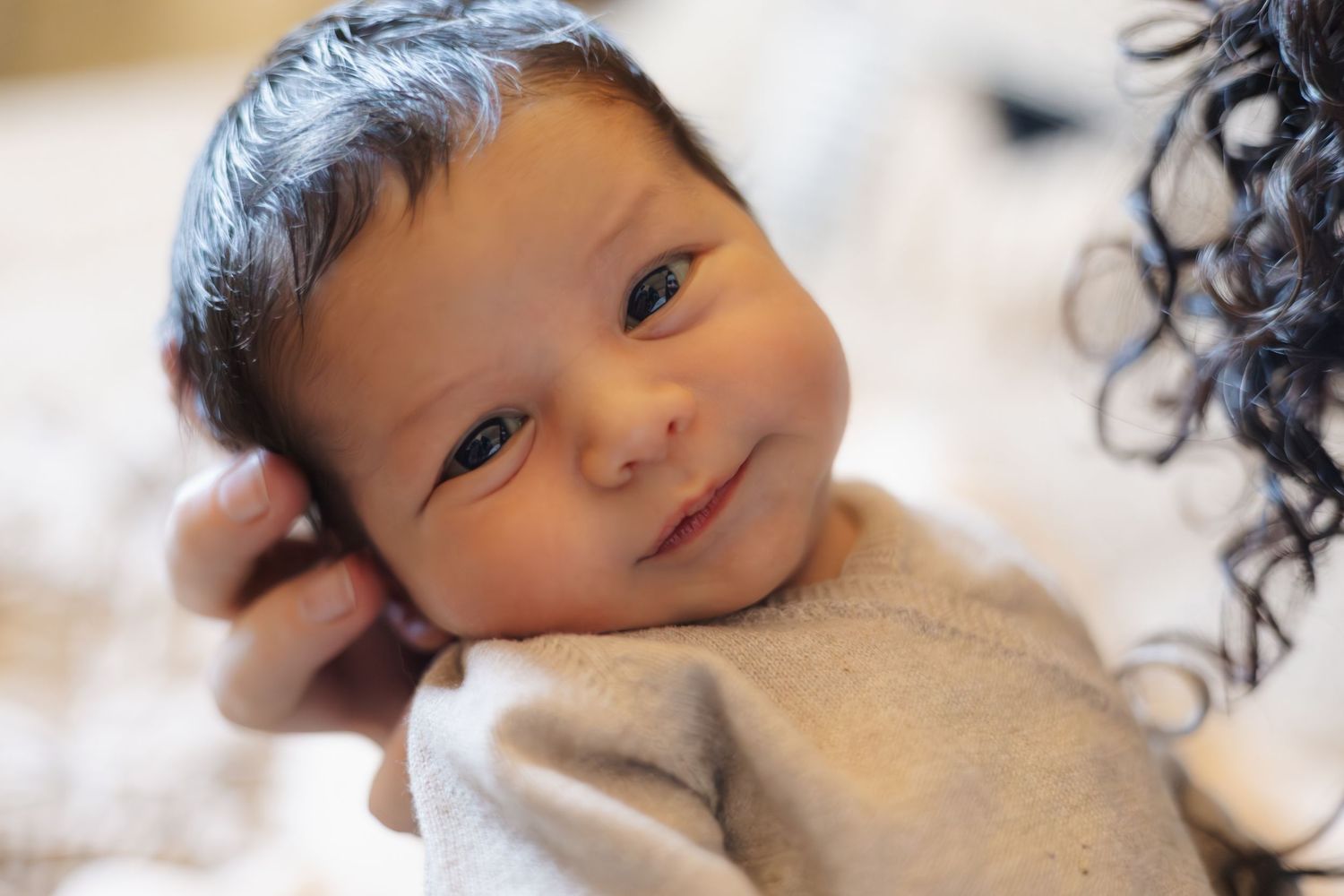 Baby wearing cozy gray sweater in soft lighting.