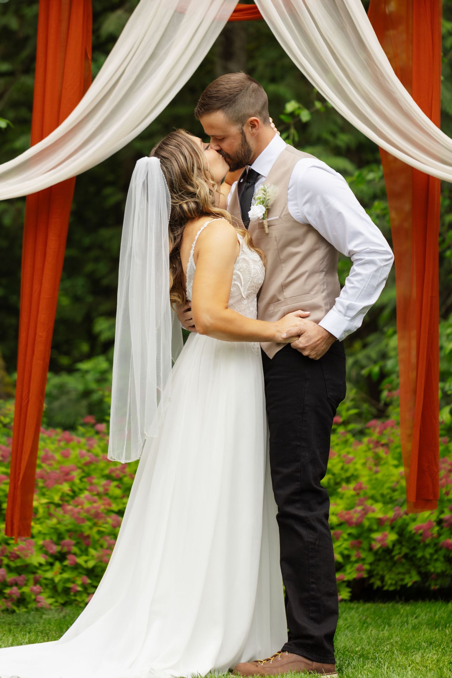 A romantic wedding sequence showing a couple embracing under white draped fabric and red pillars in a garden setting.