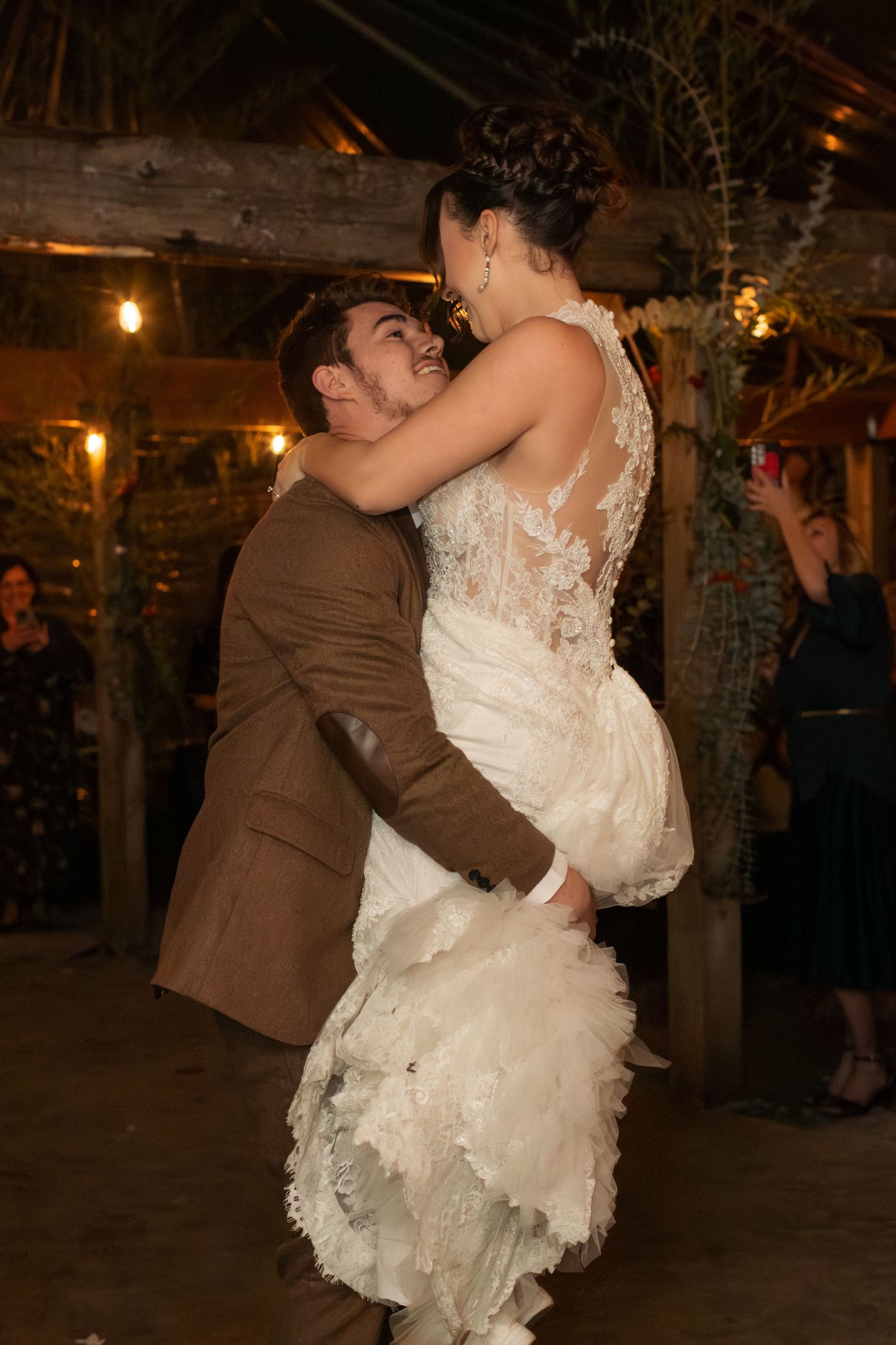 Romantic first dance moment at a rustic wedding reception with ambient lighting.