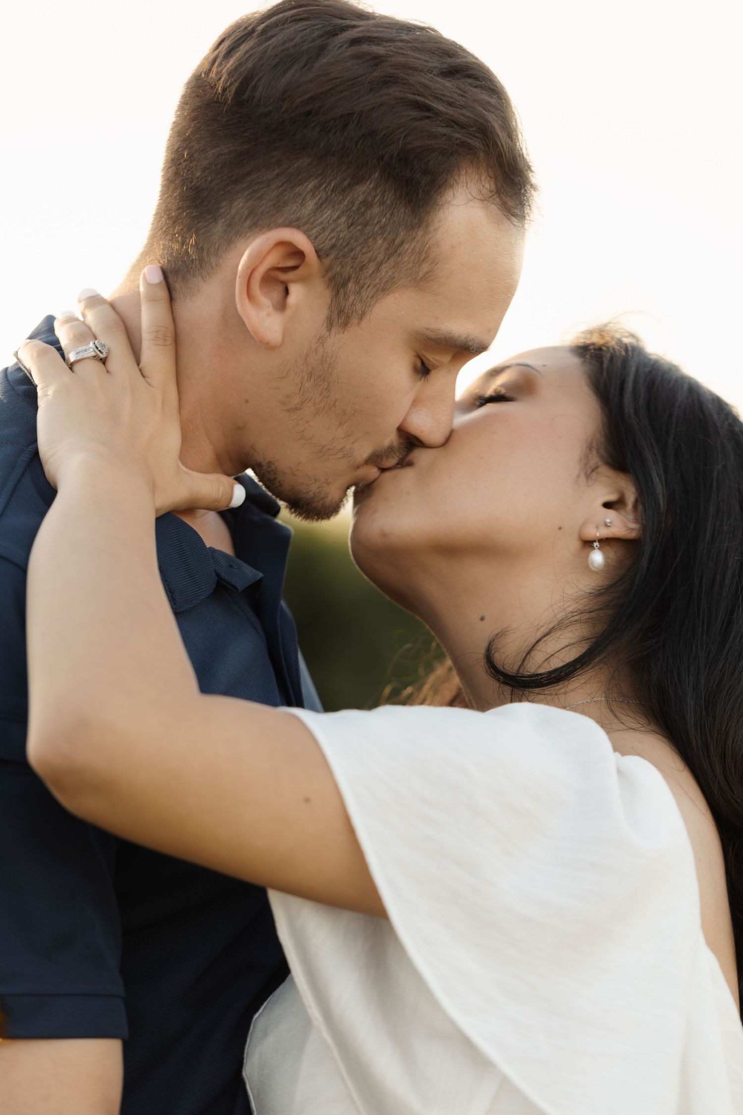 Intimate close-up of couple sharing tender moment against bright background.