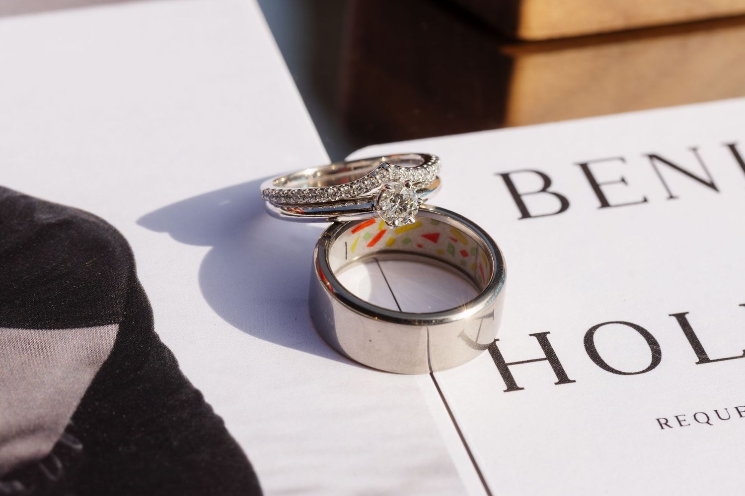 Close-up details of elegant wedding rings and jewelry on printed paper.