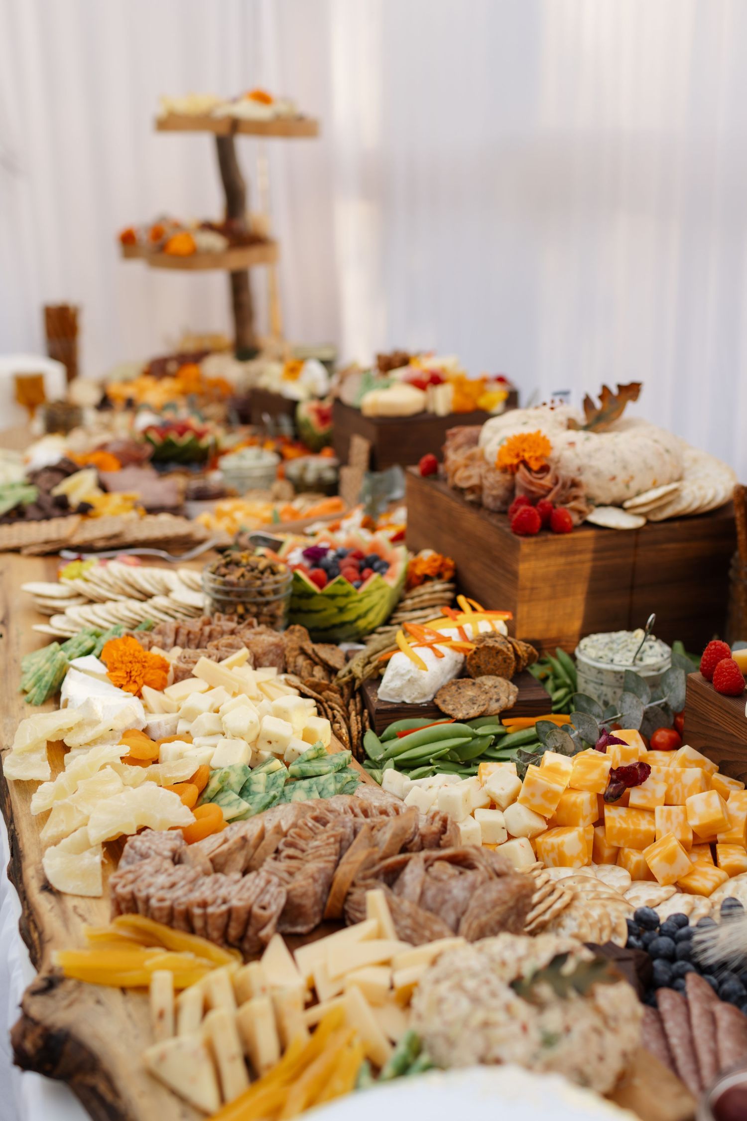 Elegant charcuterie board display with assorted cheeses, meats, fruits and nuts arranged on wooden serving platters.
