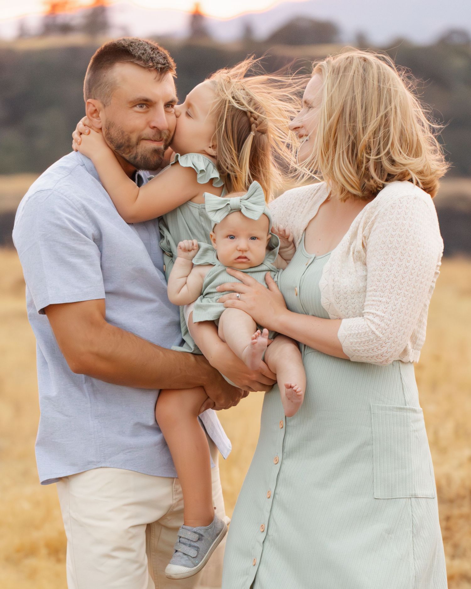 Family sharing tender moment together in golden field at sunset.