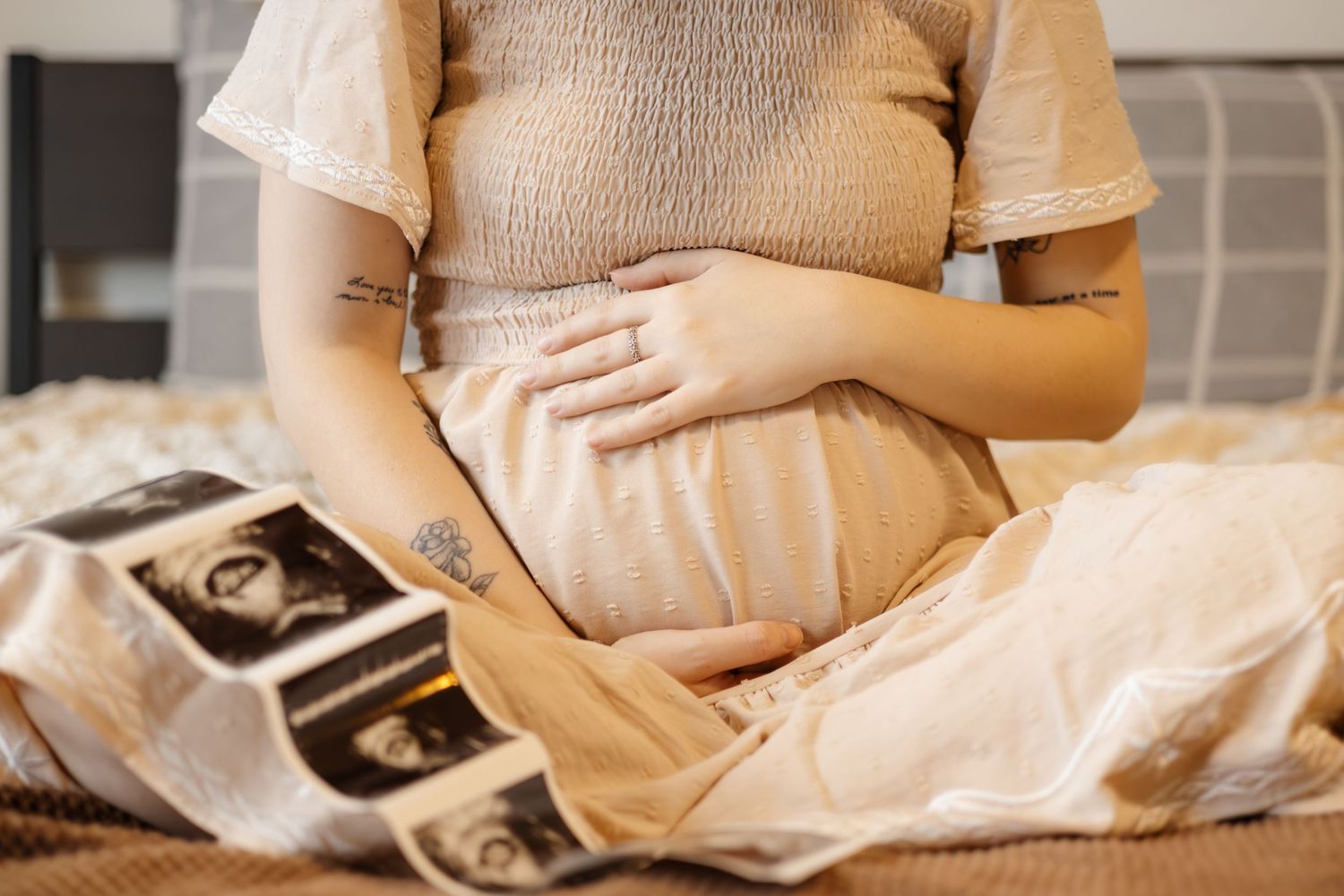 Close up view of someone holding ultrasound photos while resting on bed.