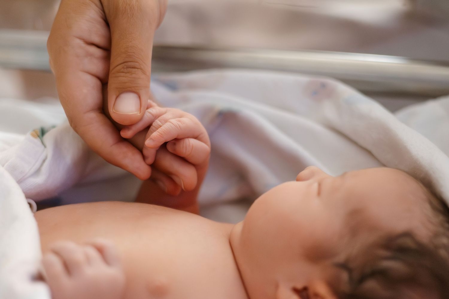 Tender moment of hands caring for newborn baby in hospital setting.