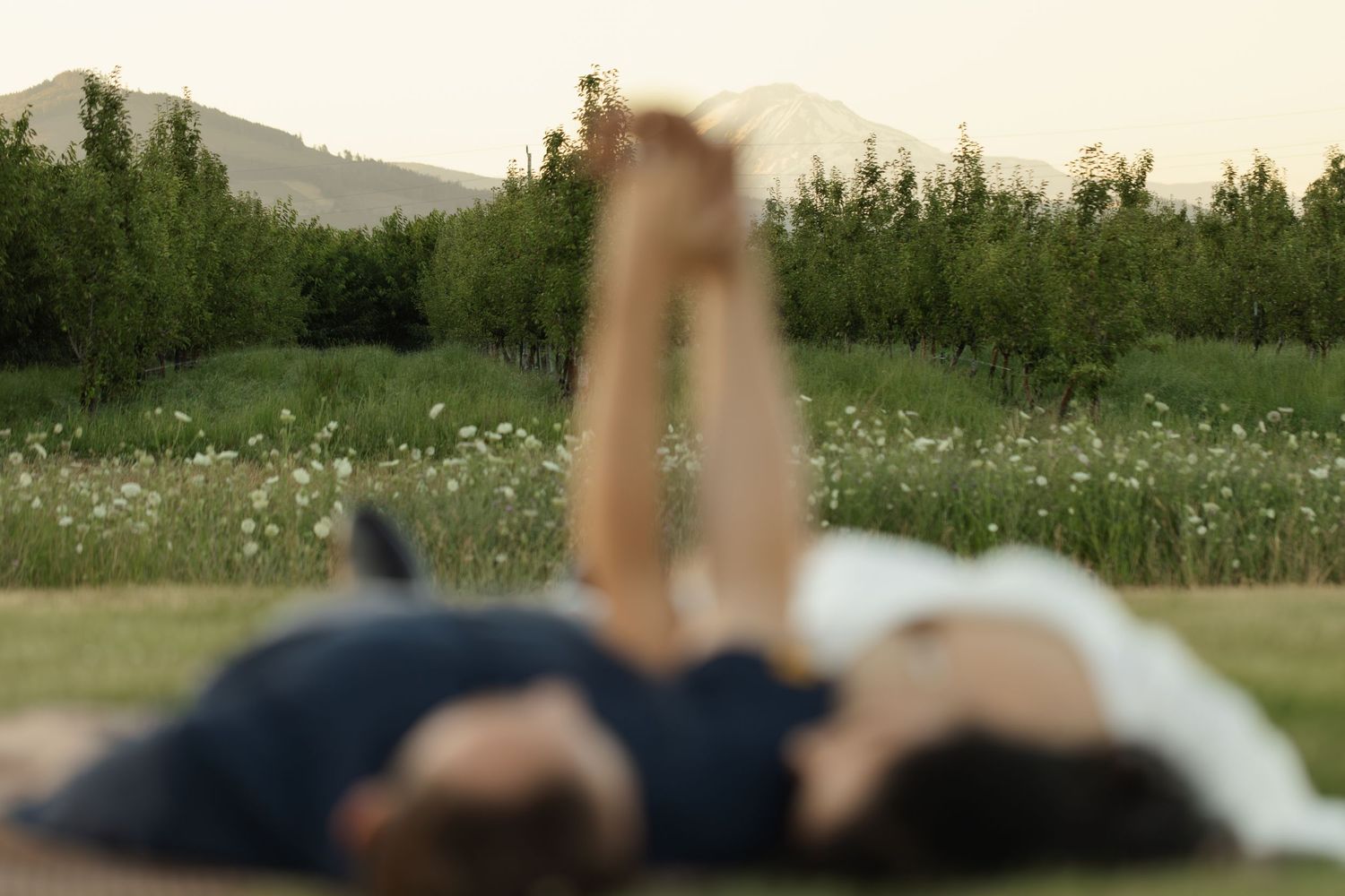 Romantic couple lying in wildflower field during golden hour photography session.