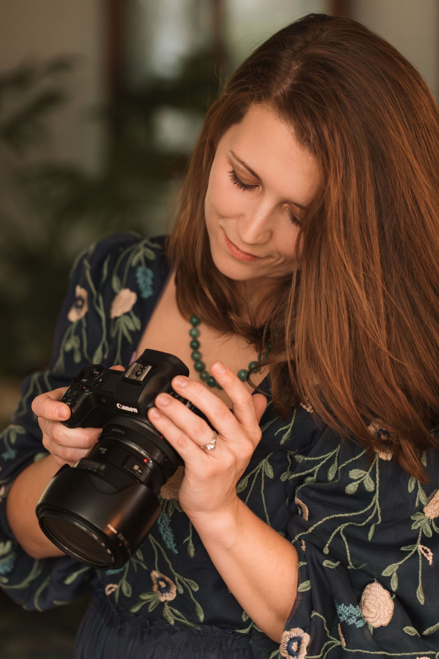 A photographer in a floral dress checks settings on their camera.