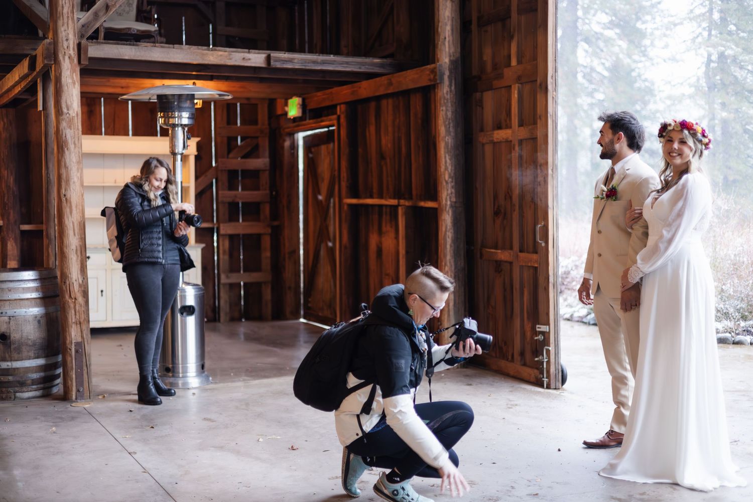 Multiple photographers capturing wedding moments in a rustic wooden barn setting.