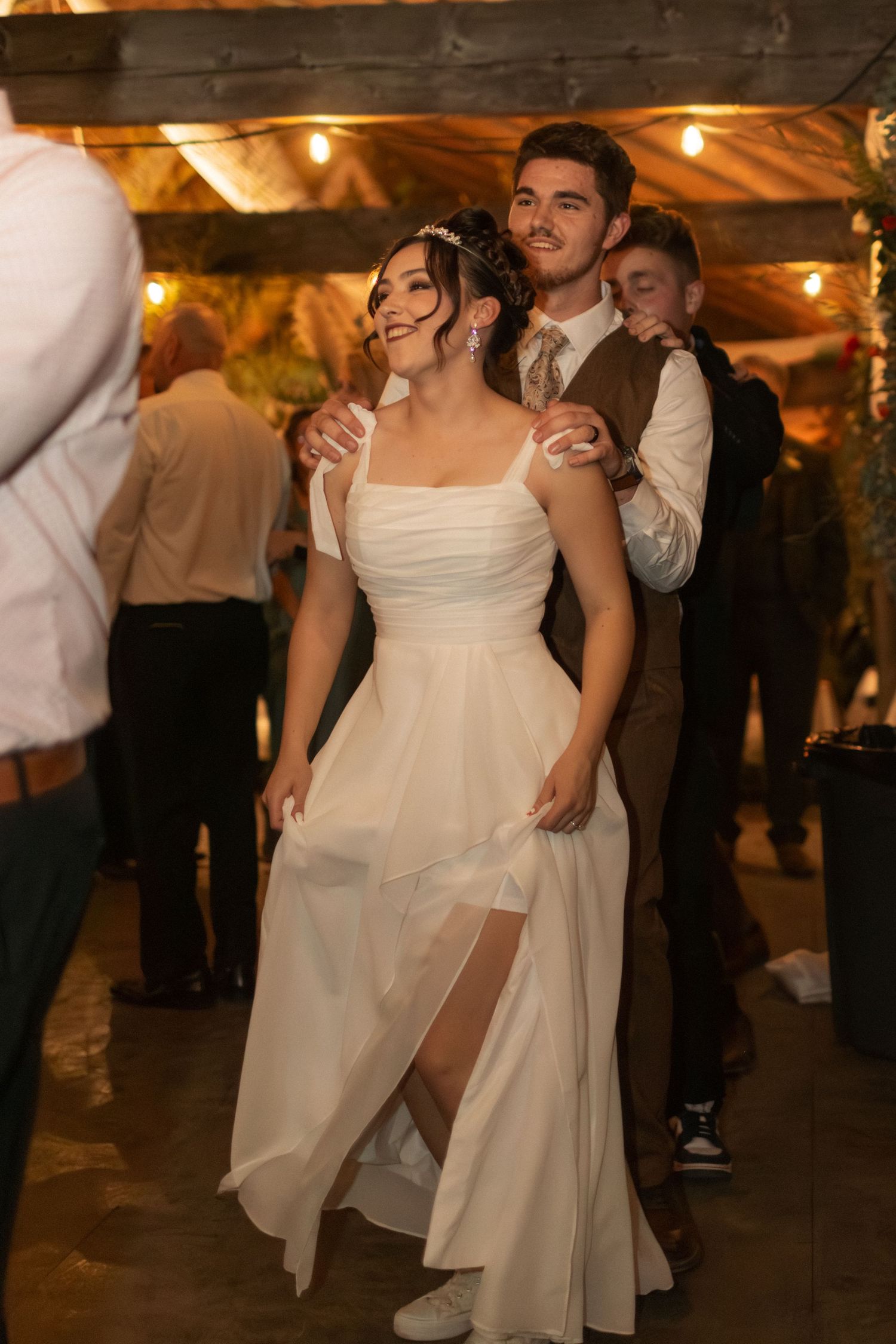 Wedding reception dance scene with flowing white dress in a rustic venue with string lights.